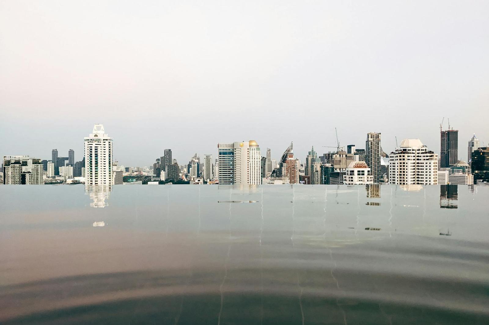 Infinity pool mirroring a hazy high-rise skyline