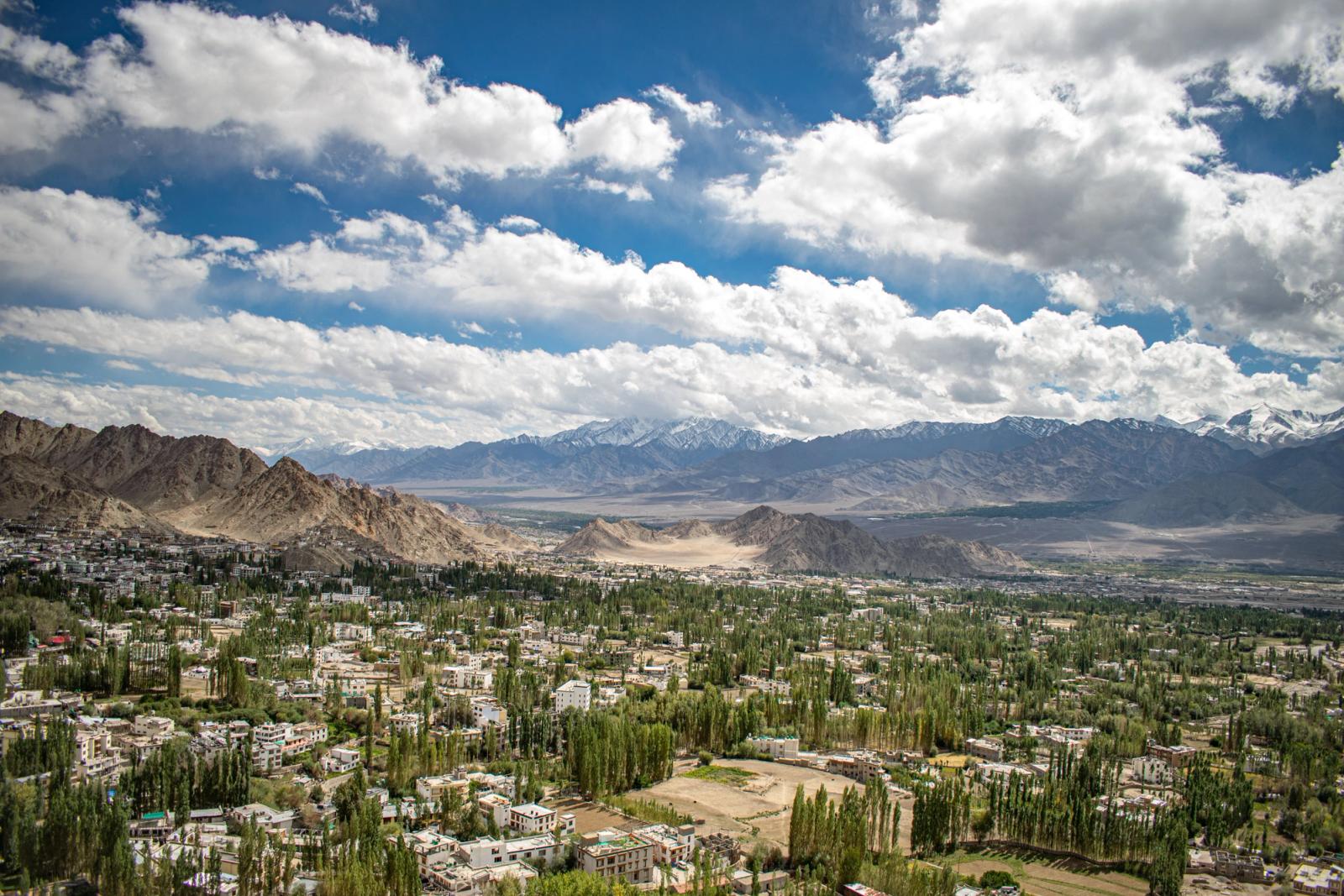 A stunning aerial view of Leh with lush greenery and majestic mountains under a vibrant sky
