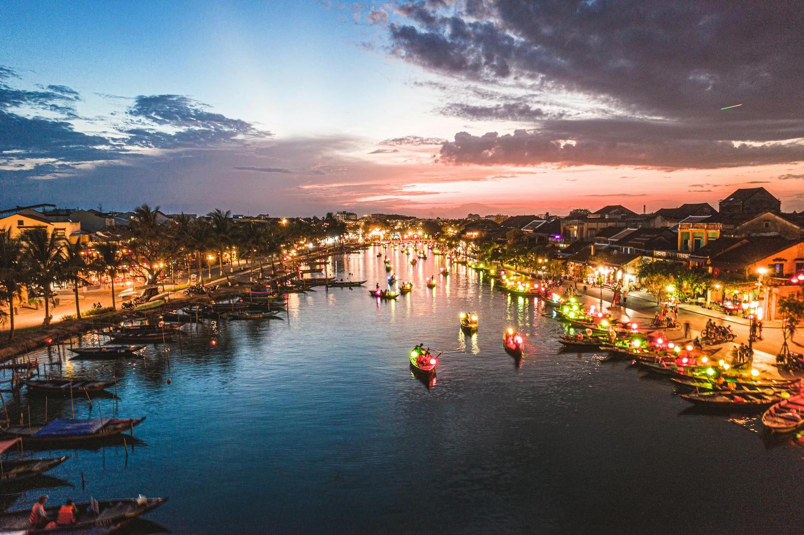 Riverside old town glowing with lanterns and boats at dusk