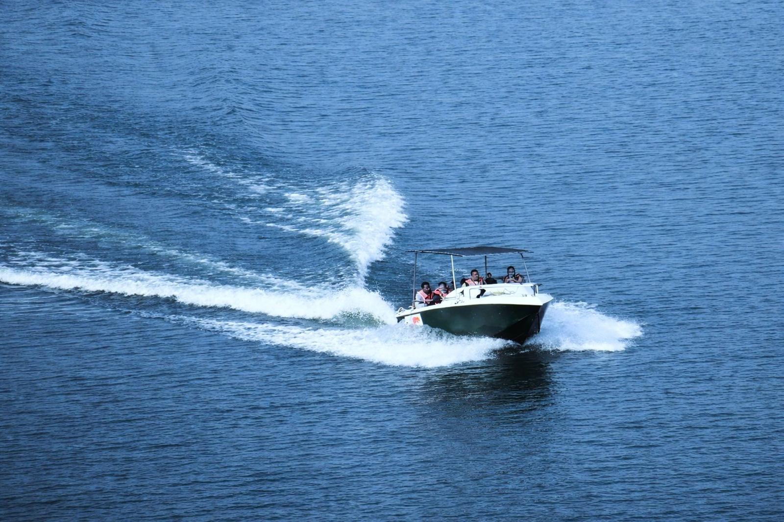 Speedboat carrying passengers cuts across open water leaving a wake