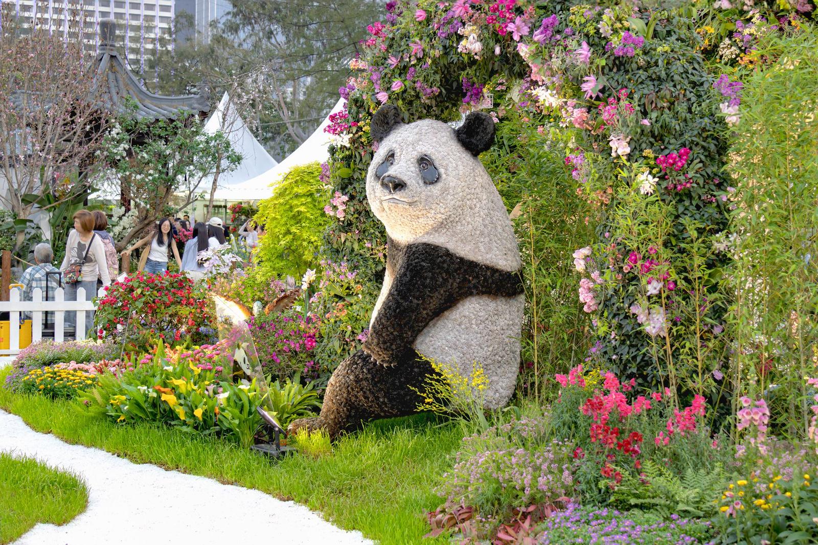 Panda-shaped topiary sculpture surrounded by a flower garden display