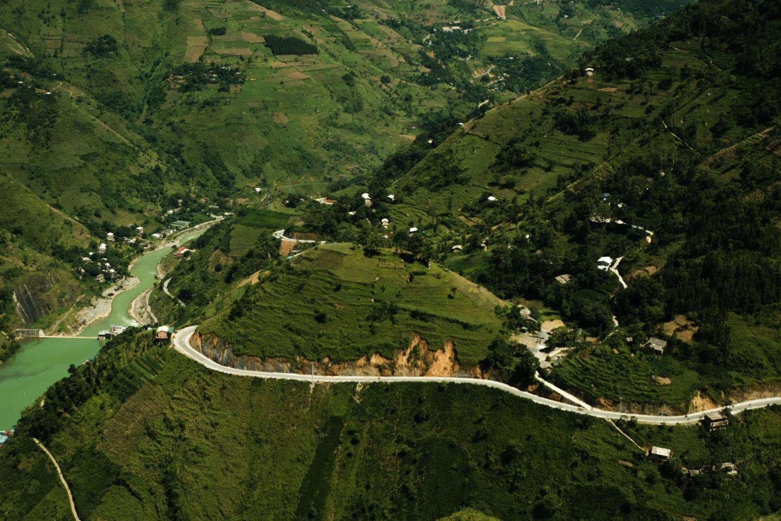 Aerial shot of lush green valleys with winding roads and river view