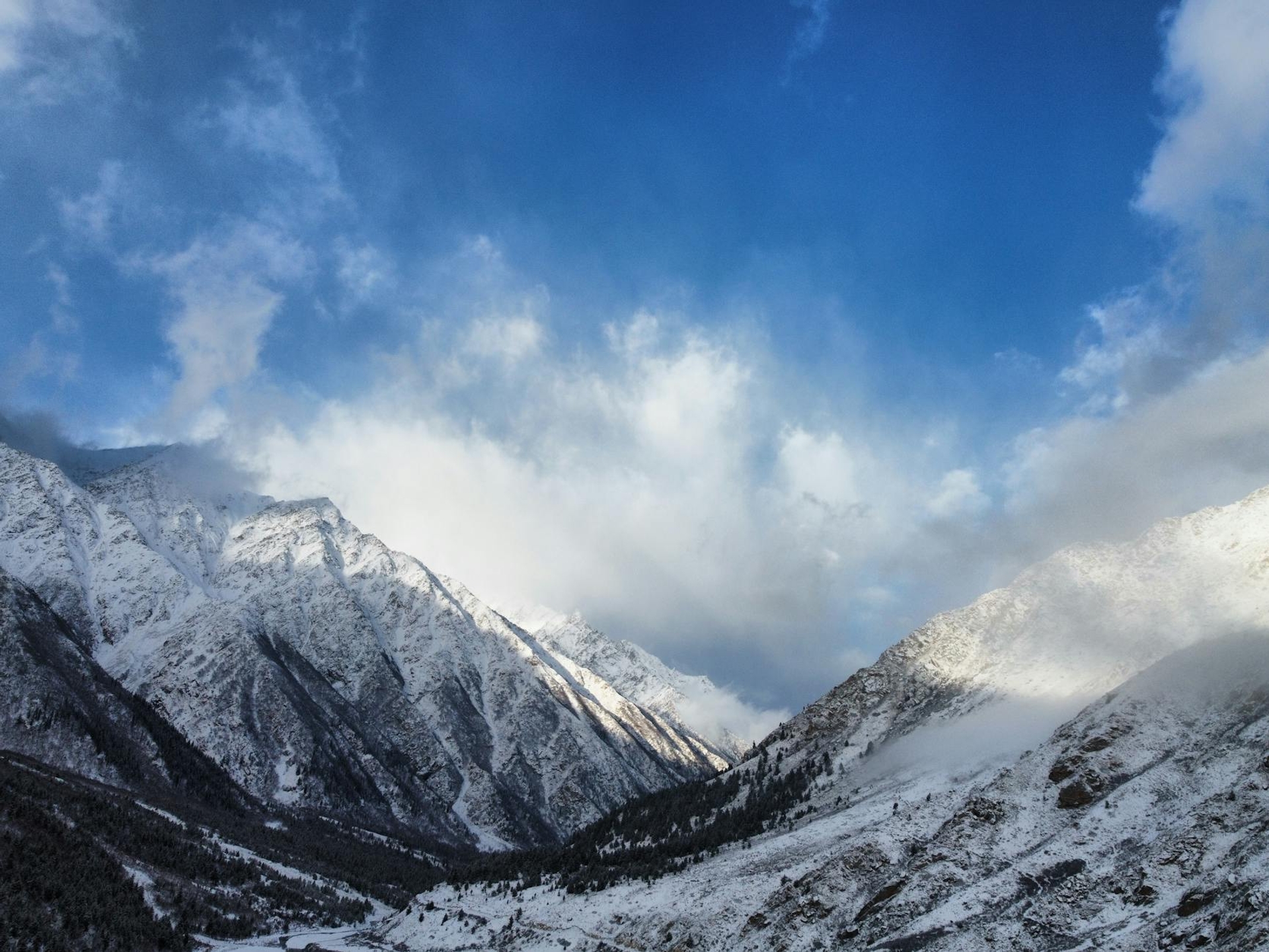 Snow-dusted mountain ridges rising into a cloud-streaked sky