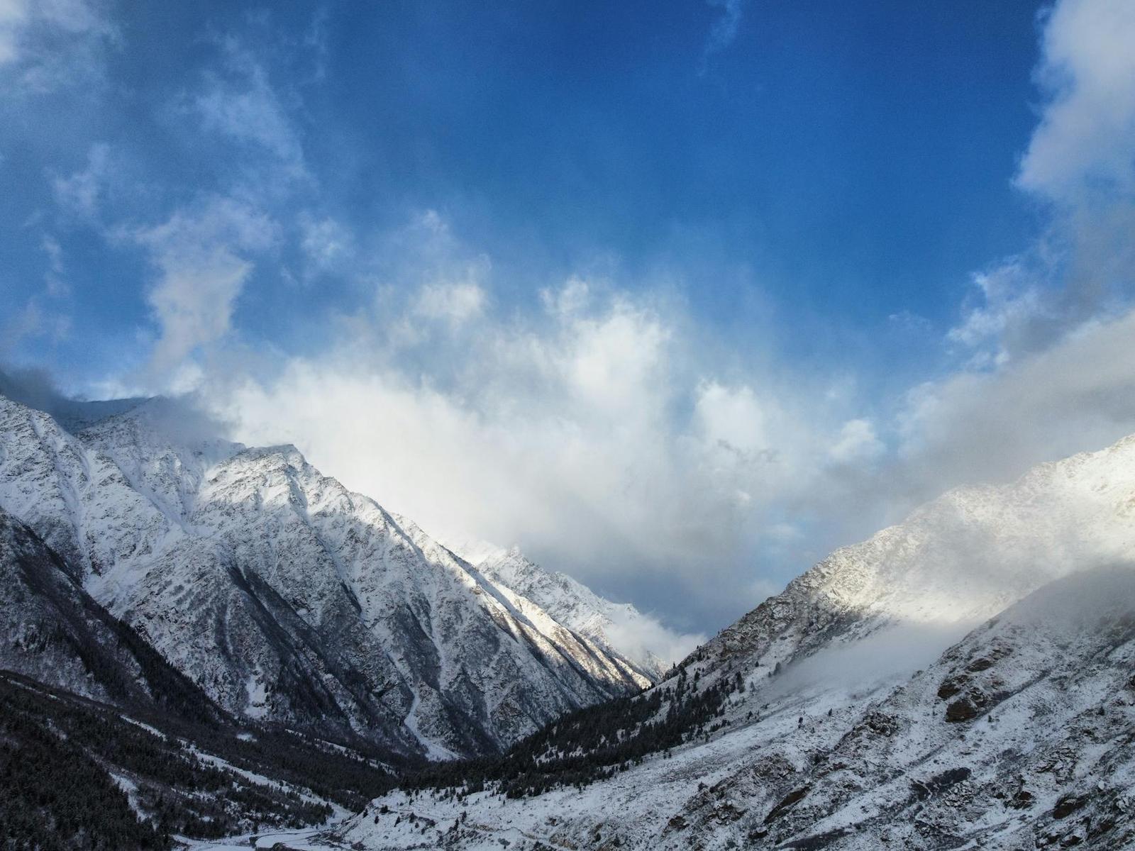 Snow-dusted mountain ridges rising into a cloud-streaked sky