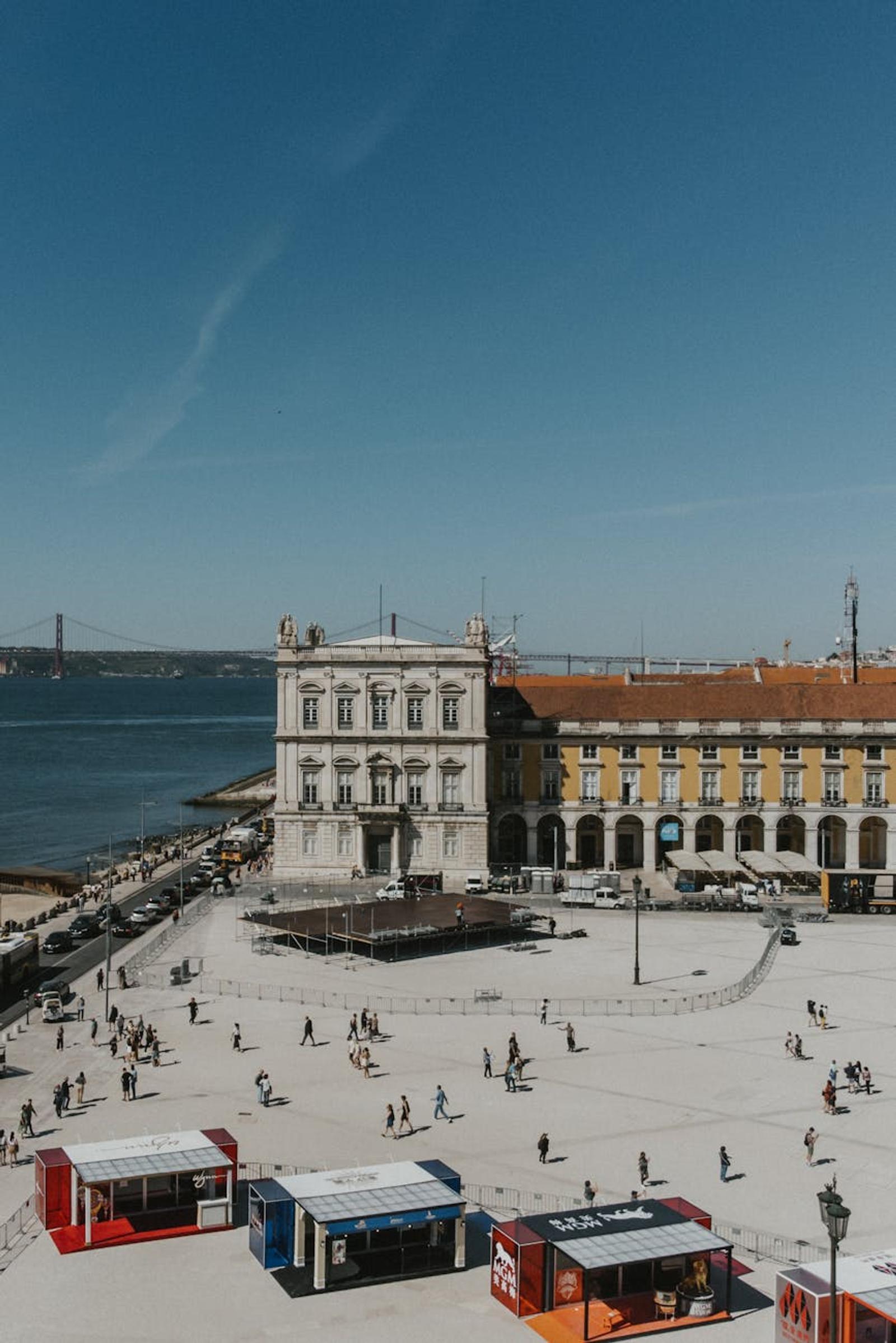 Grand plaza building beside a waterfront with a distant bridge