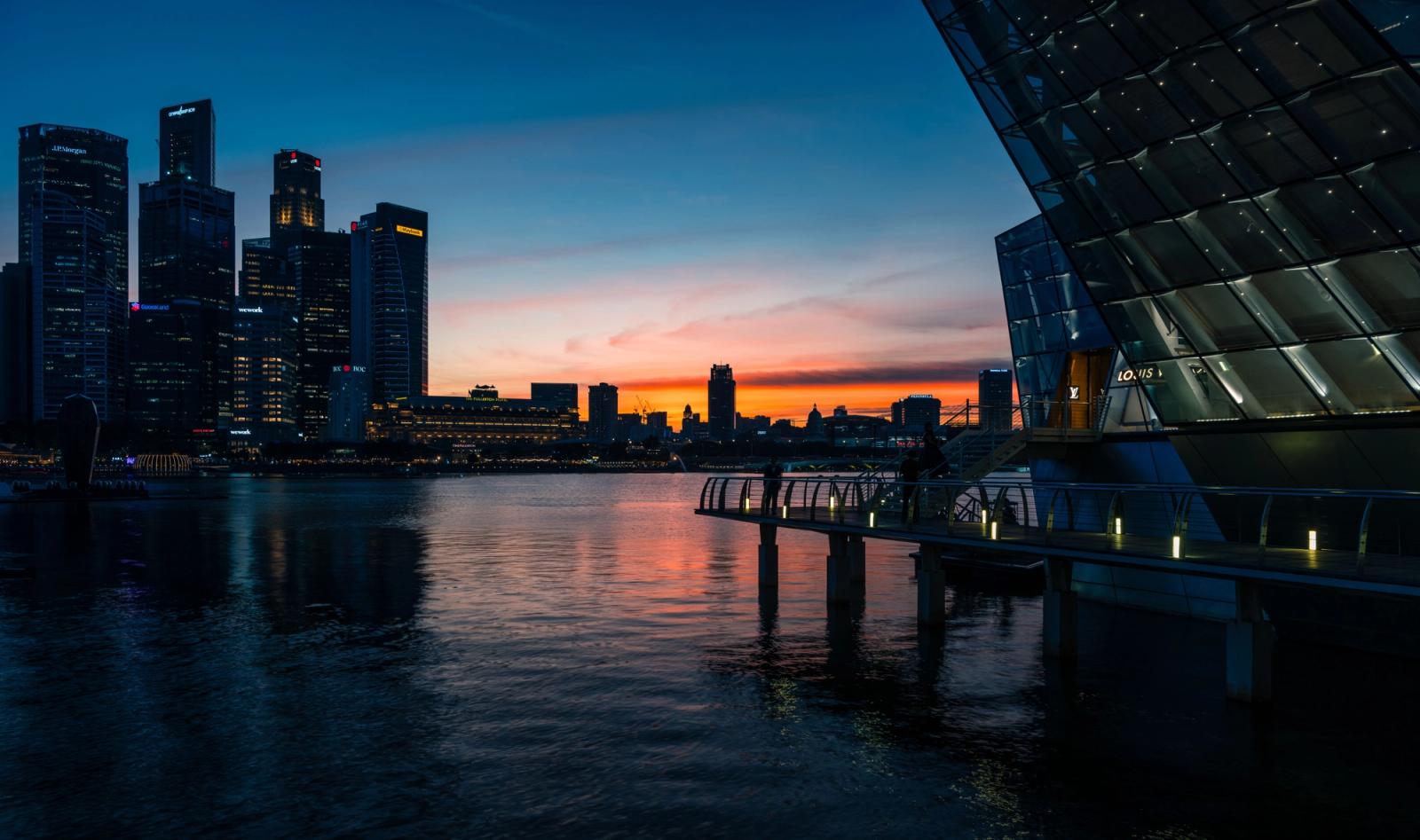 Beautiful view of Singapore skyline and Marina Bay at sunset with city lights reflecting on the water