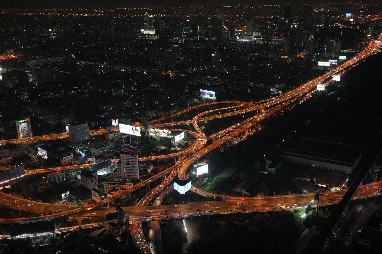 Aerial night view of a busy highway interchange glowing with orange traffic light trails