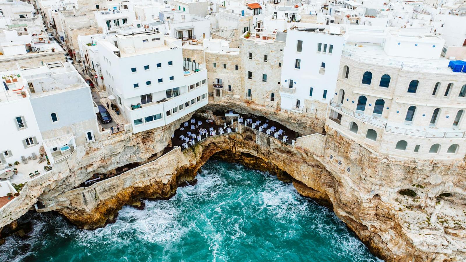 Aerial view of white buildings perched over a rocky sea inlet