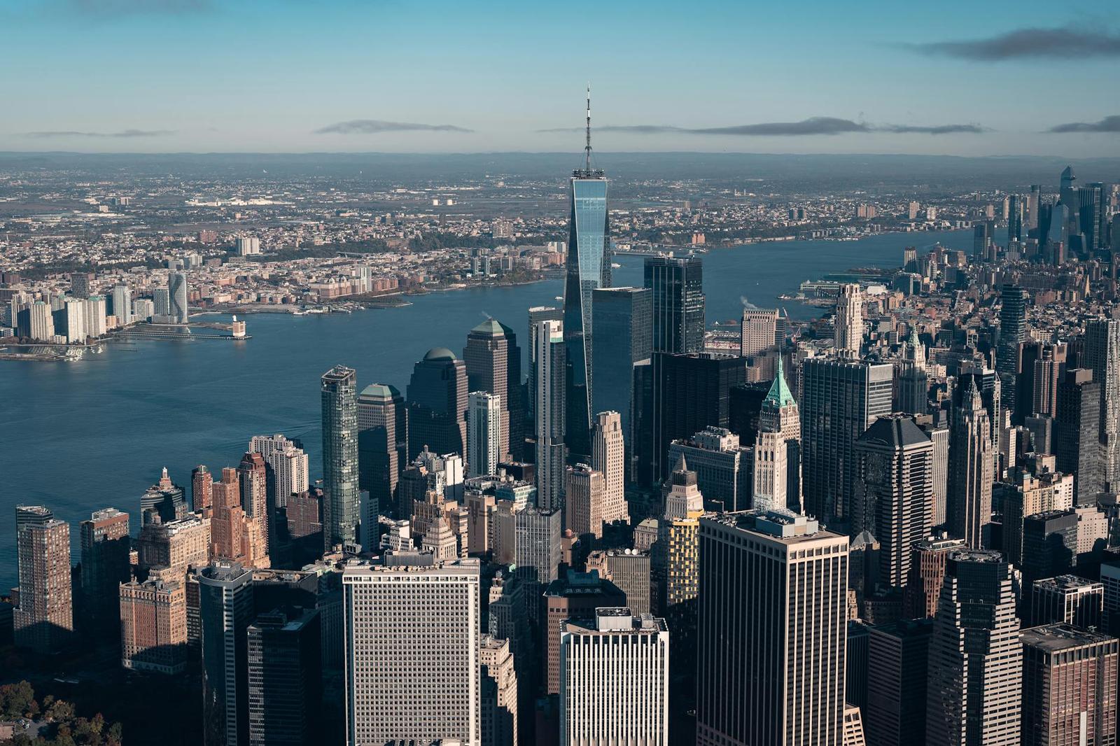 Aerial view of a dense skyline with a tall tapered spire beside a river