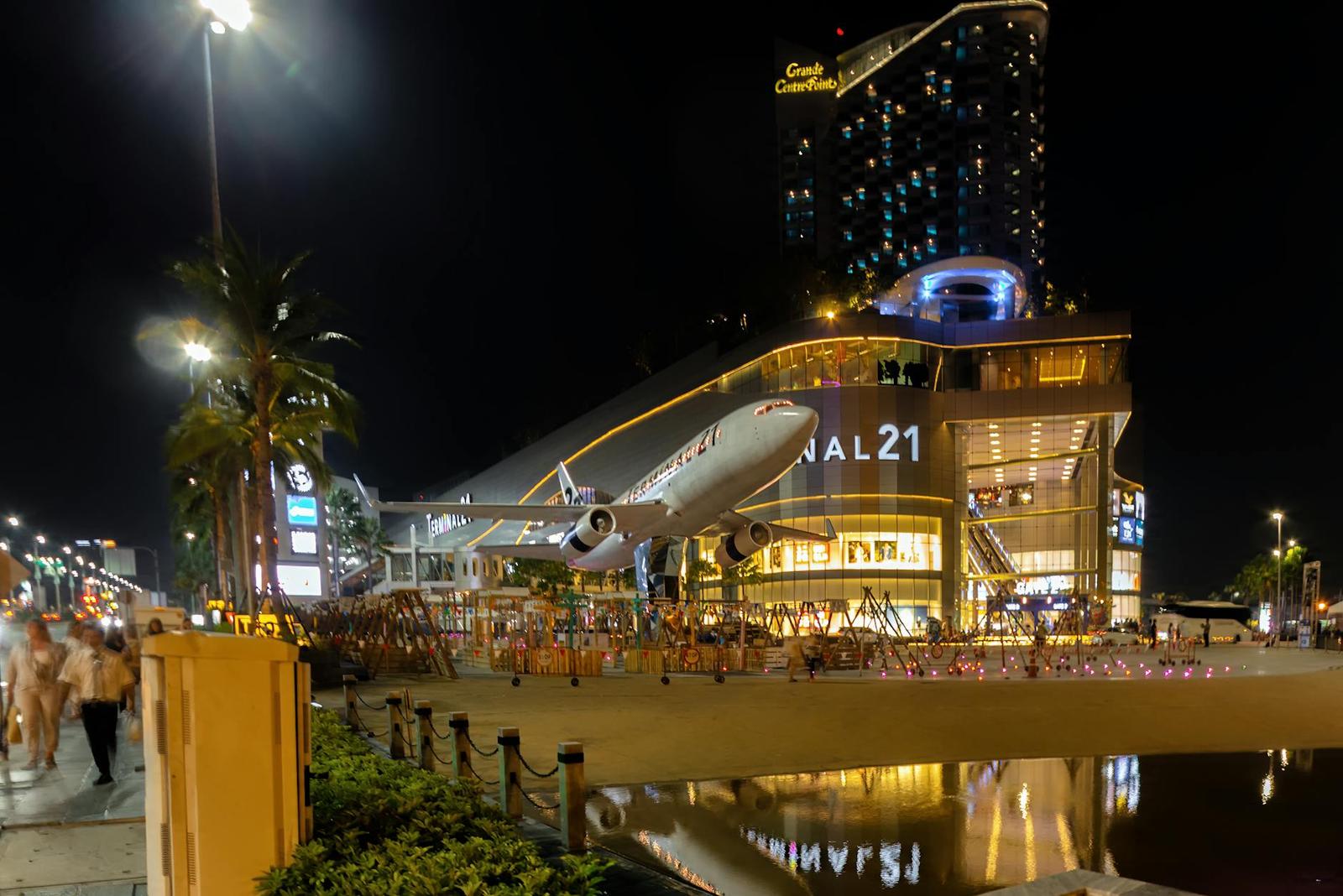 A model airplane fuselage jutting from a mall facade lit up at night