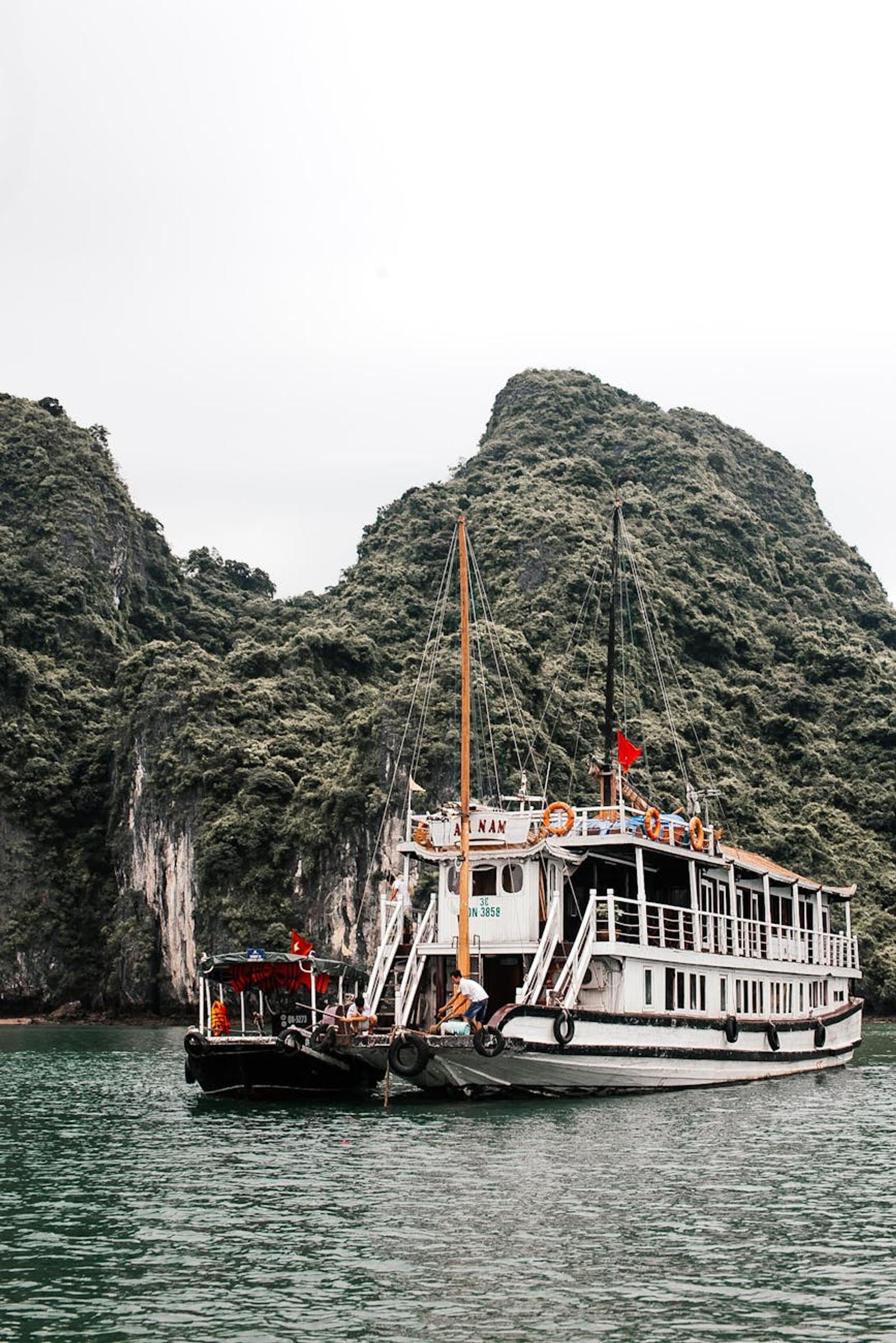 Tour boat anchored beside towering limestone karsts