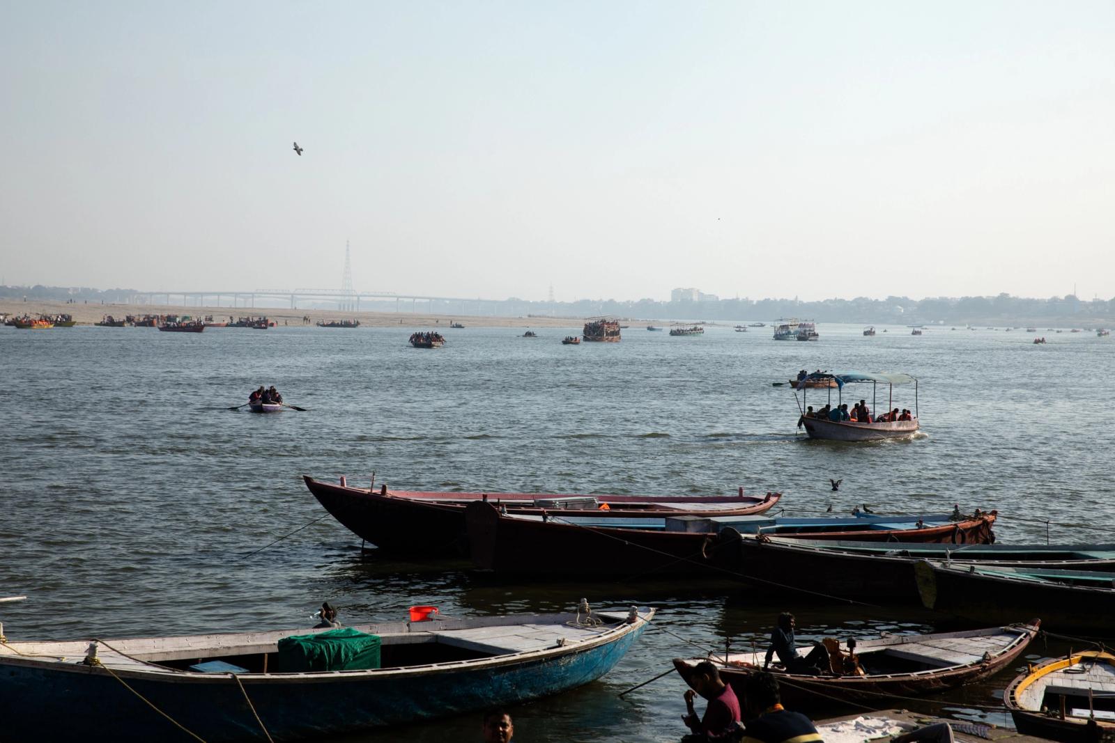 Boats gently float on the Ganges River in Varanasi, India, under a clear blue sky