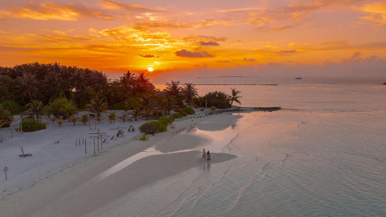 A couple walking along the shoreline at sunset