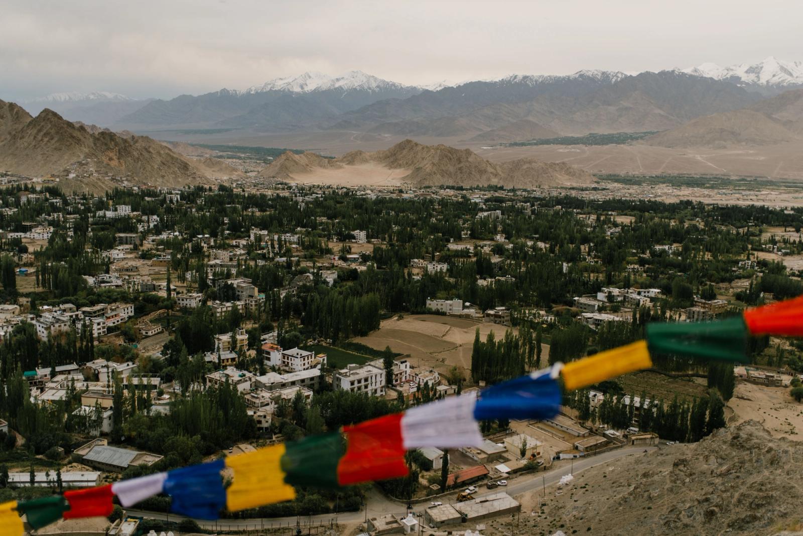 A breathtaking aerial view of Leh, India with vibrant prayer flags and majestic mountain backdrop