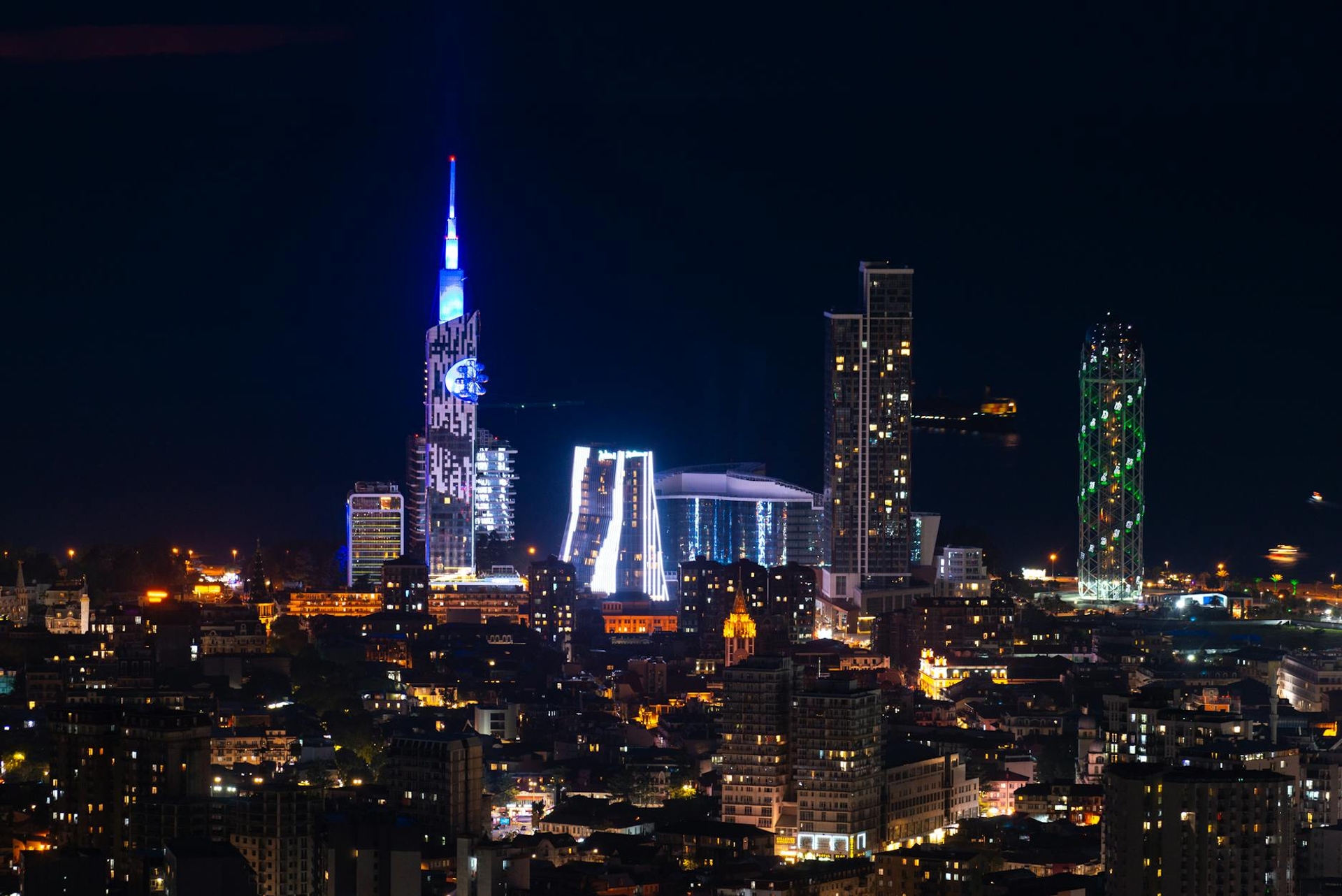 A city skyline glows with illuminated skyscrapers against a dark night sky