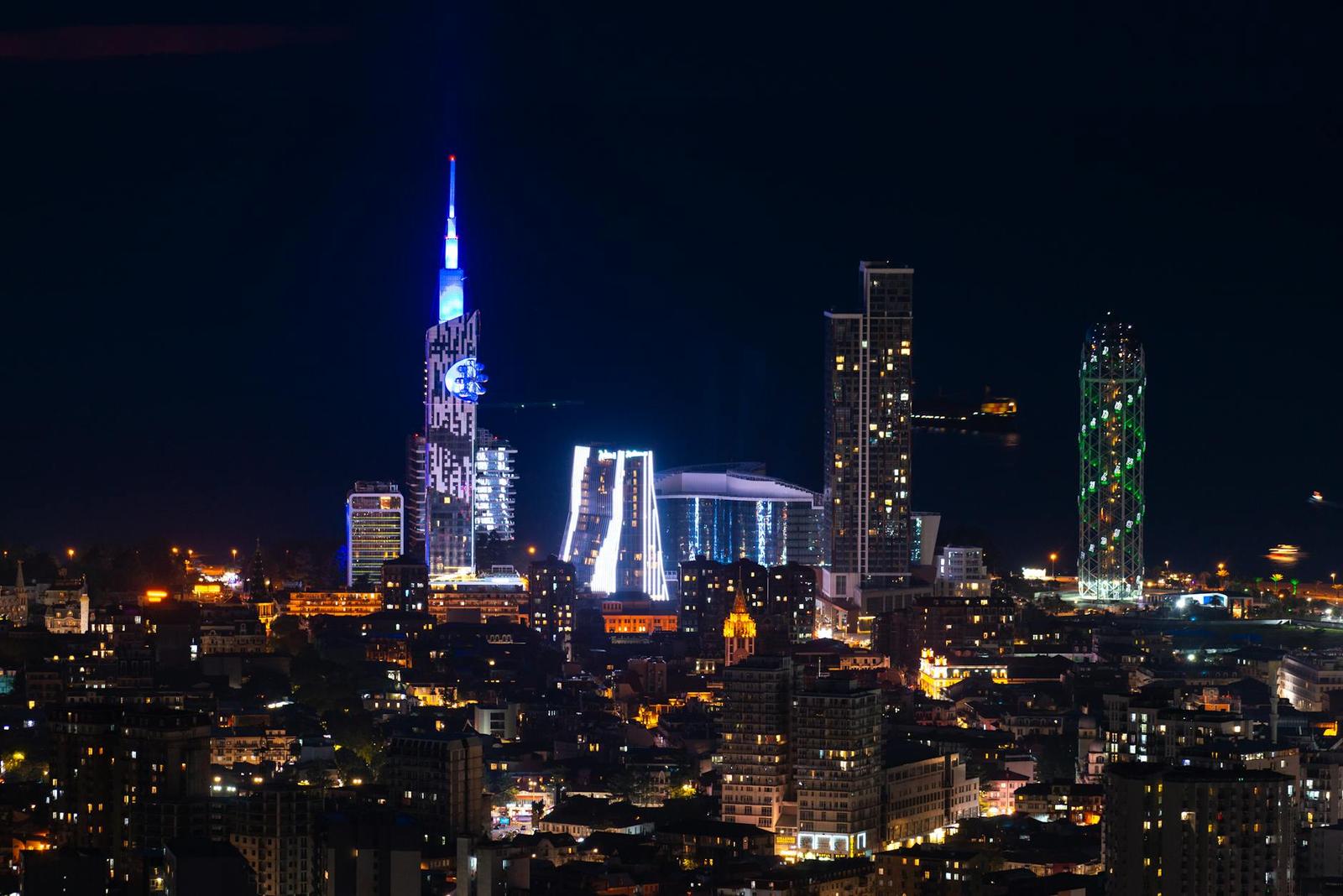 A city skyline glows with illuminated skyscrapers against a dark night sky