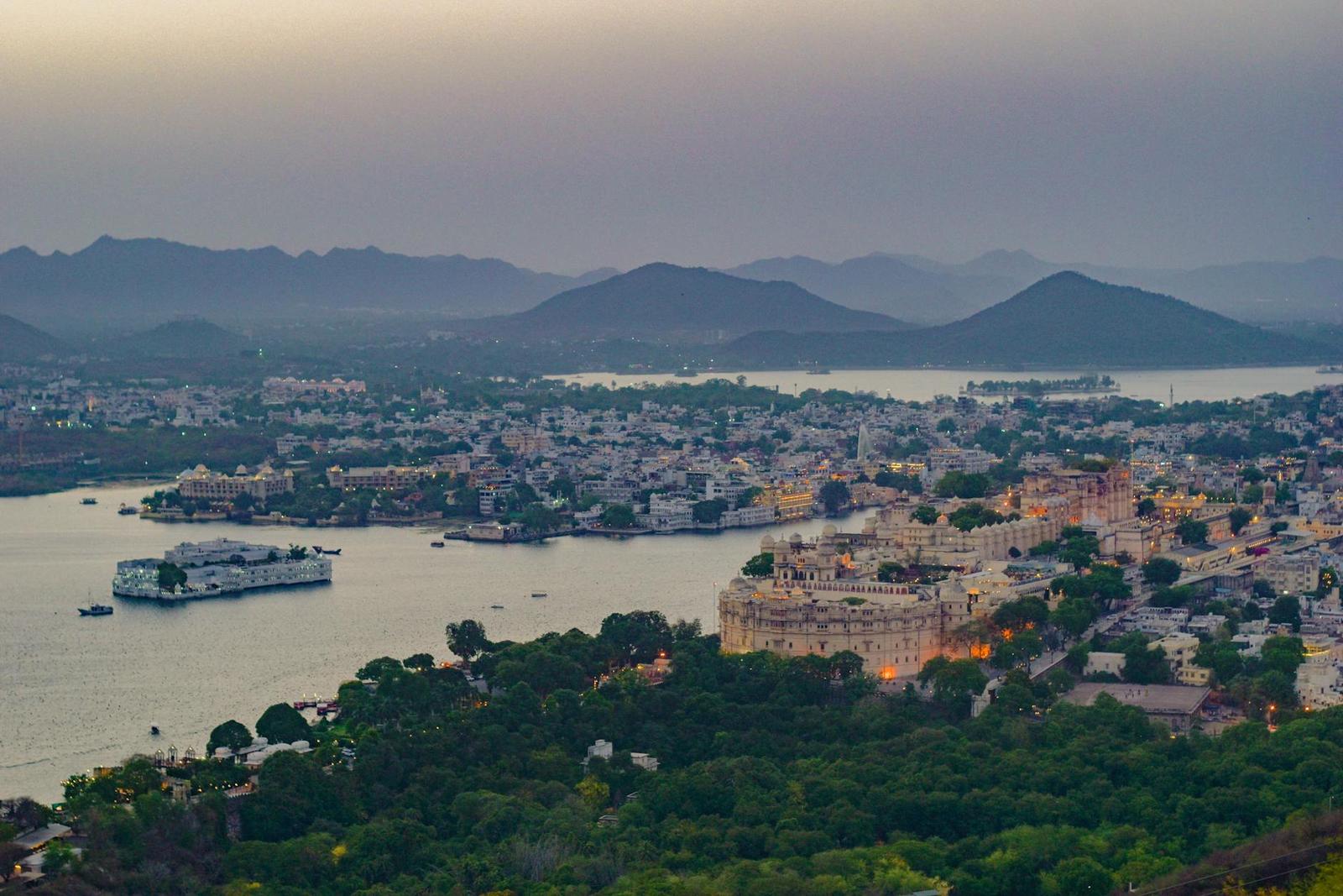 A breathtaking aerial view of Udaipur, Rajasthan, India, featuring a serene lake at twilight