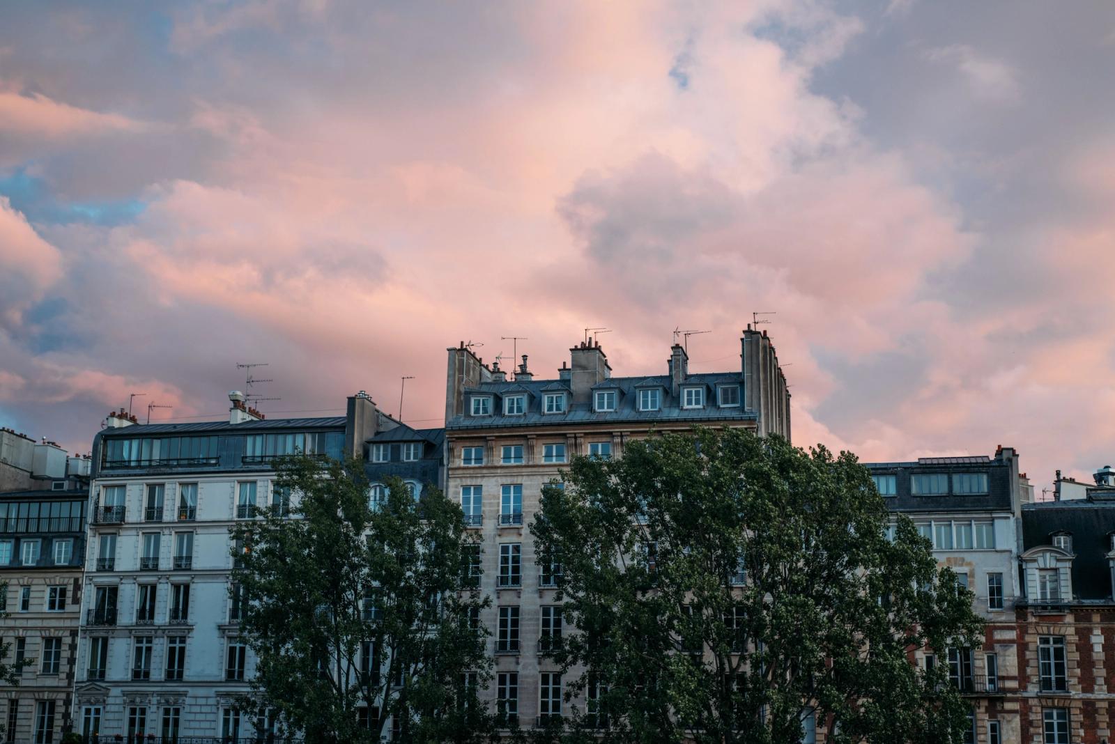 Elegant Parisian architecture with a pink cloud-filled sky, showcasing classic urban charm