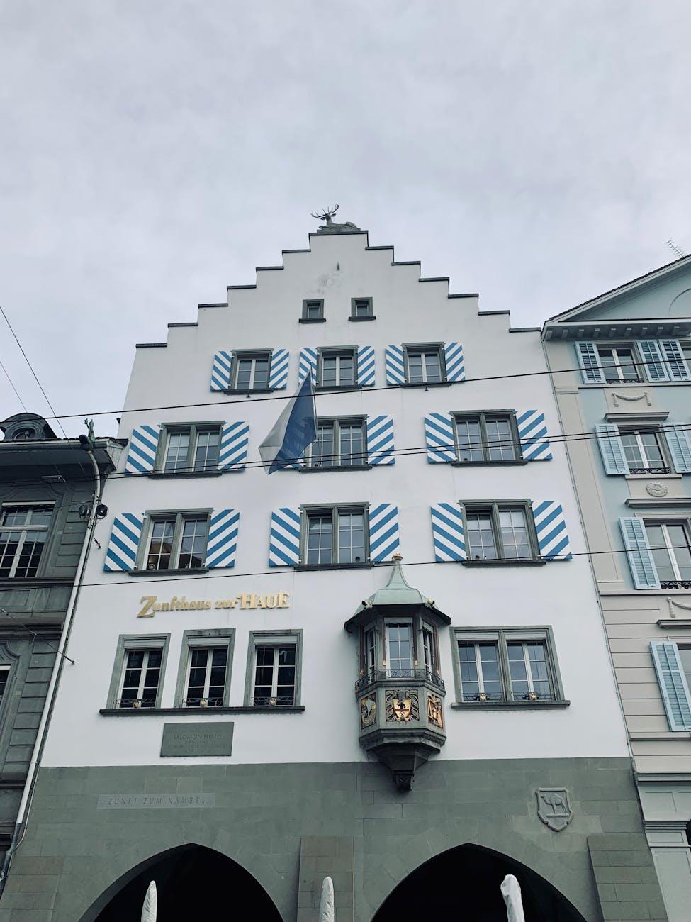 Historic guild house facade with striped shutters and a corner turret