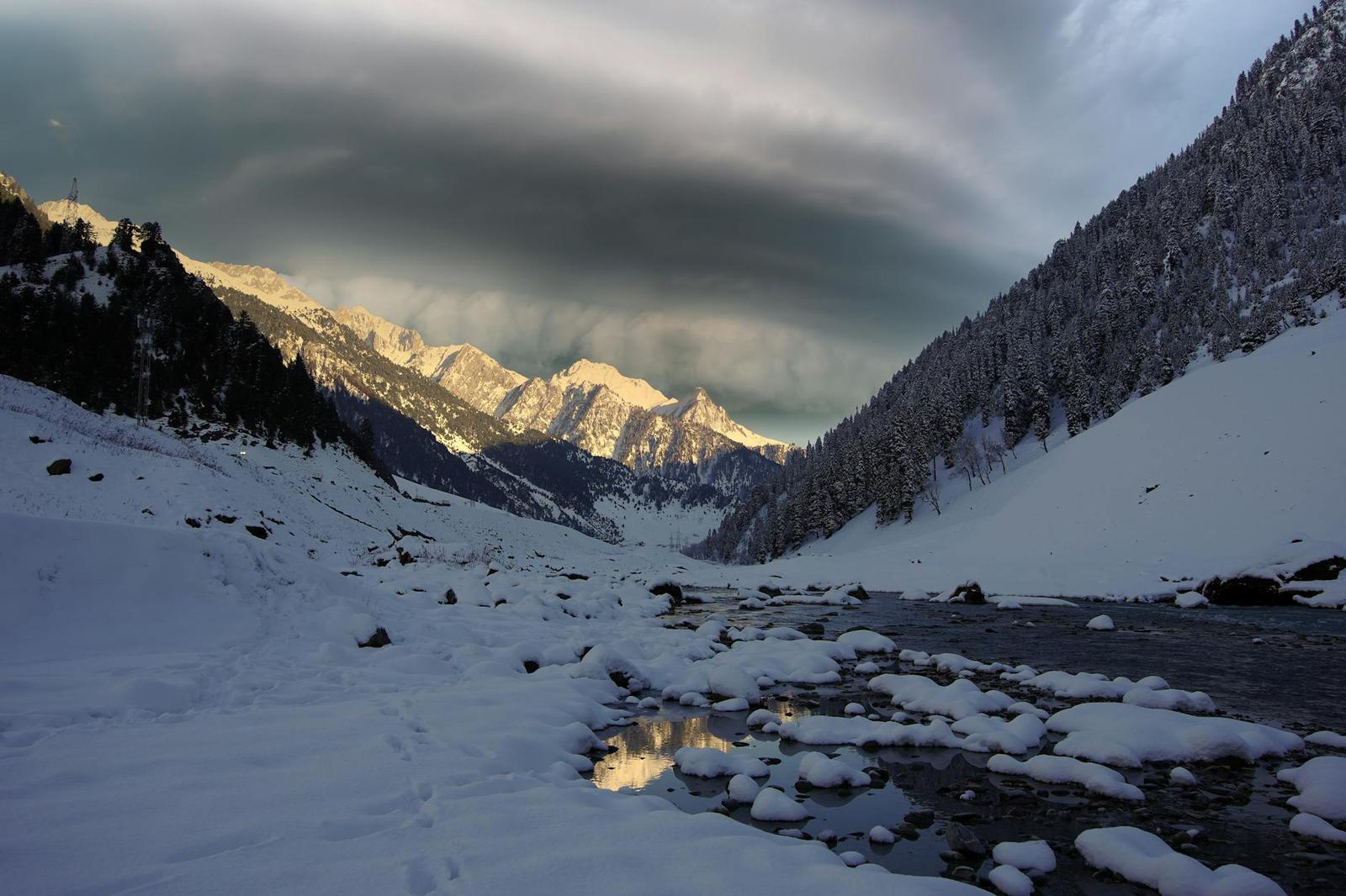 A breathtaking view of snow-covered mountains and serene river in Sonamarg, Kashmir during winter