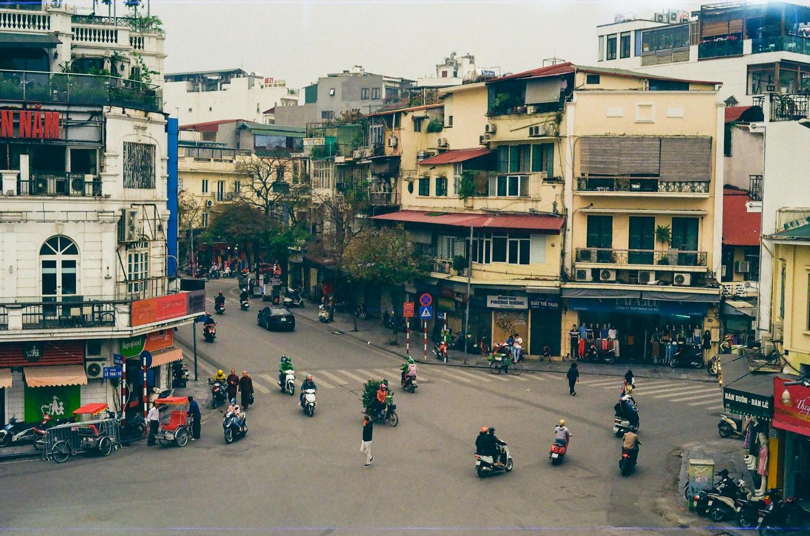 Elevated view of a busy old-quarter street intersection filled with scooters