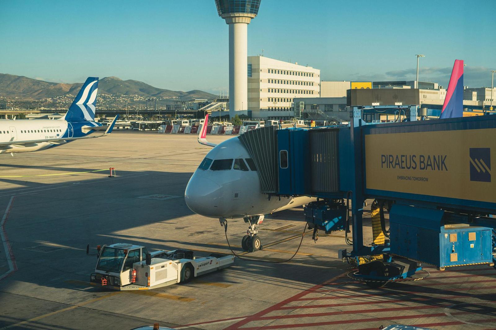 A passenger jet parked at an airport gate beside a control tower