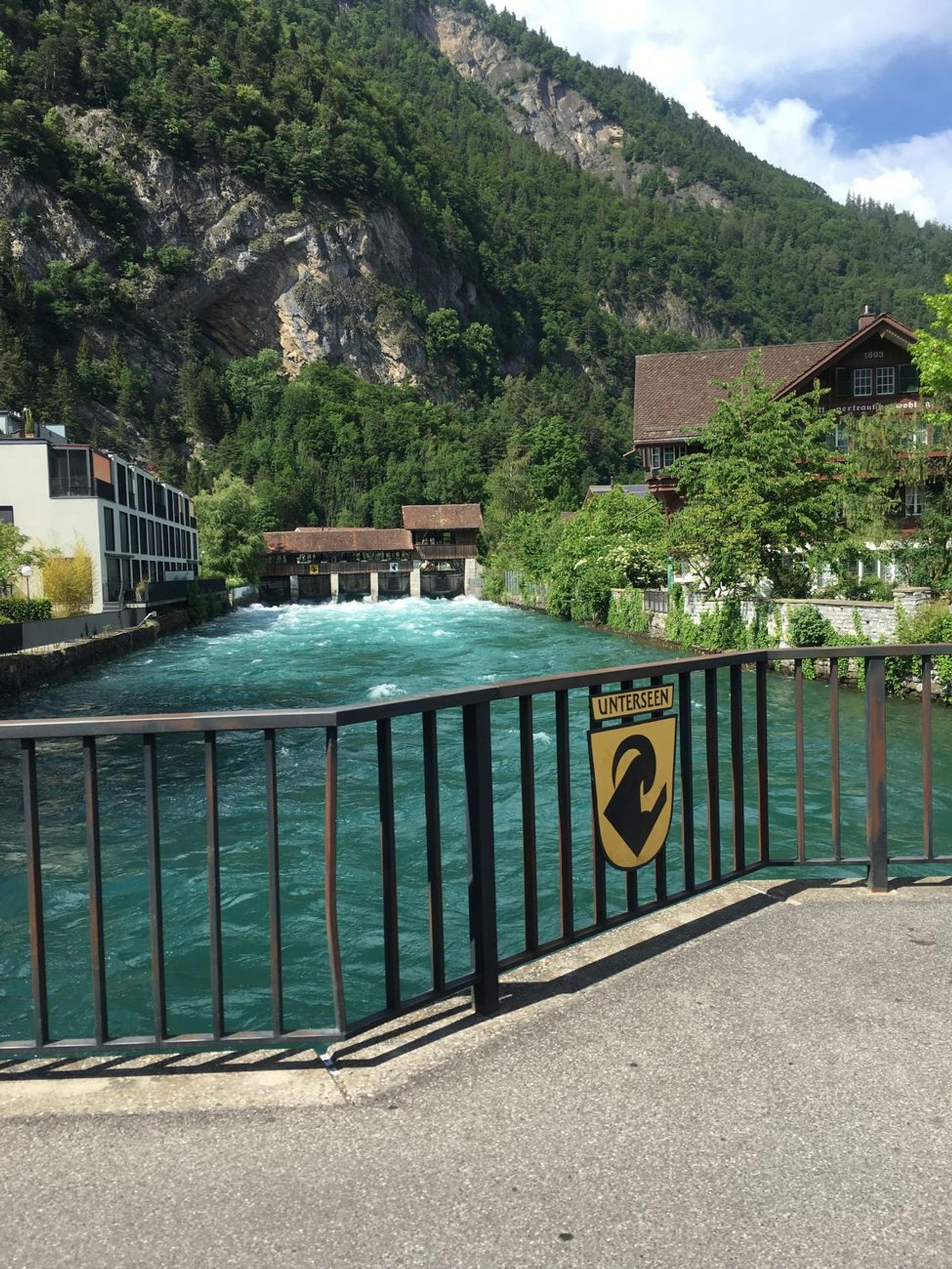 Beautiful river in Interlaken, Switzerland bordered by lush greenery and charming buildings on a sunny day