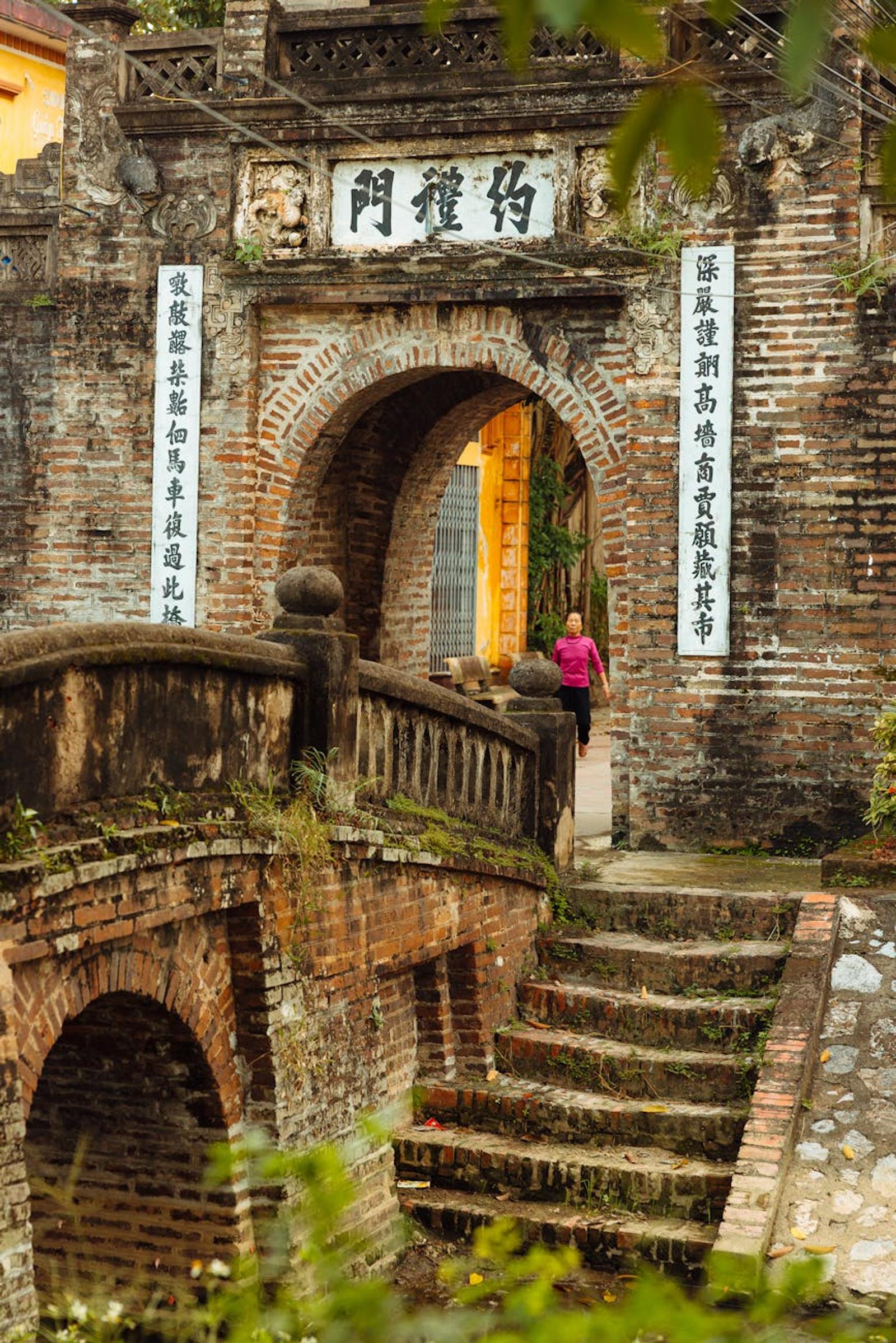 Historic Vietnamese gate and brick bridge capturing traditional architecture and cultural heritage