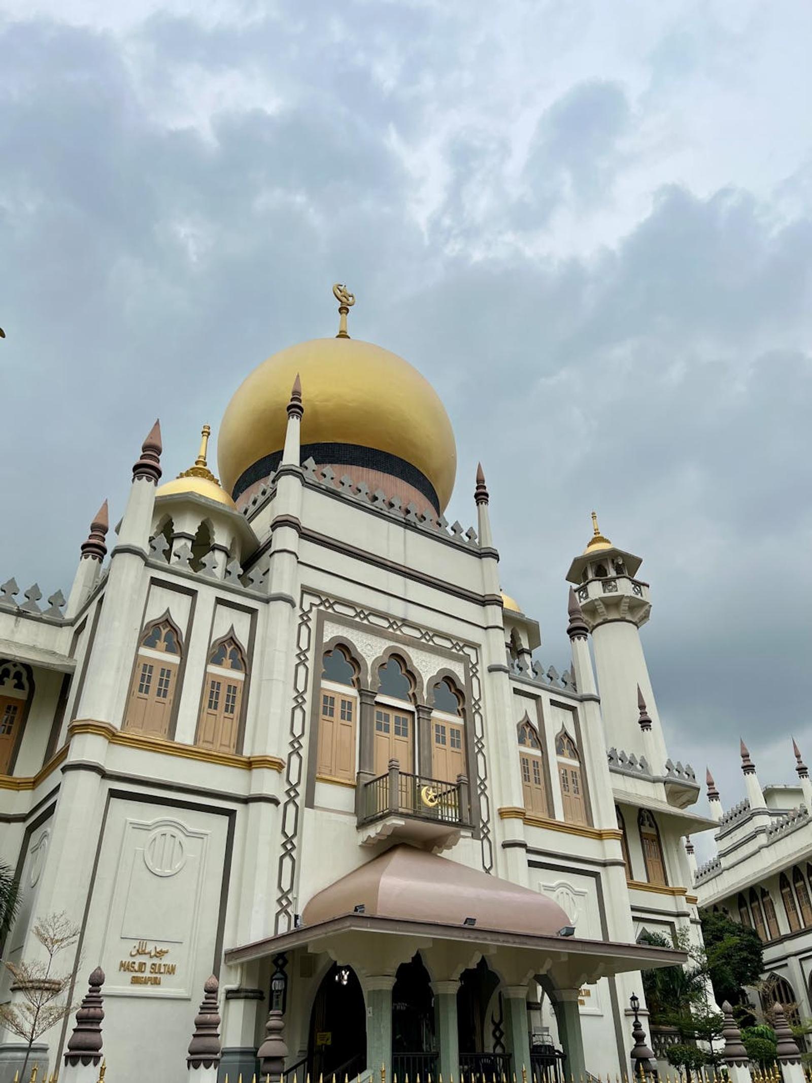 Golden-domed mosque with minarets under a cloudy sky