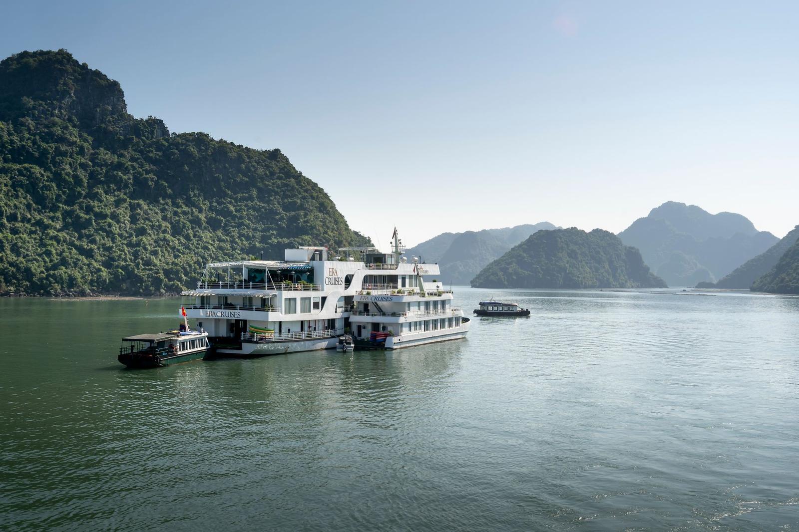 Cruise boat anchored among forested limestone peaks on calm bay waters