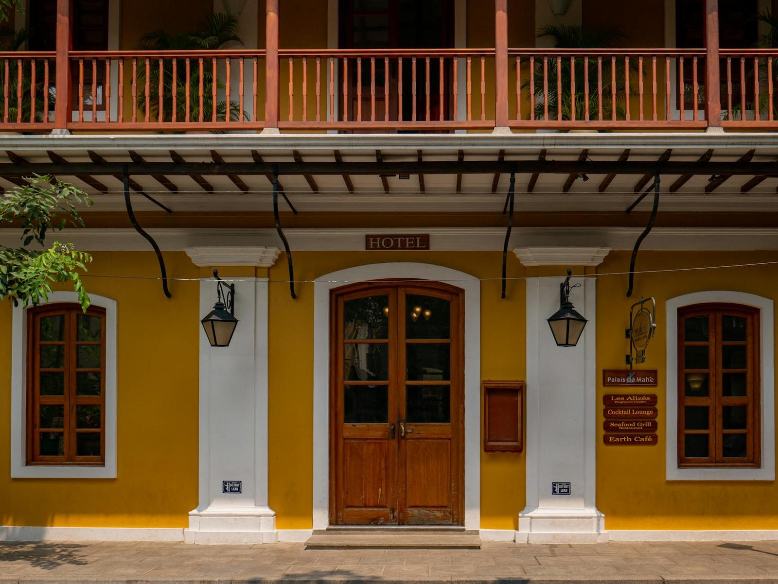 A colonial-style yellow hotel facade with wooden balconies and lanterns