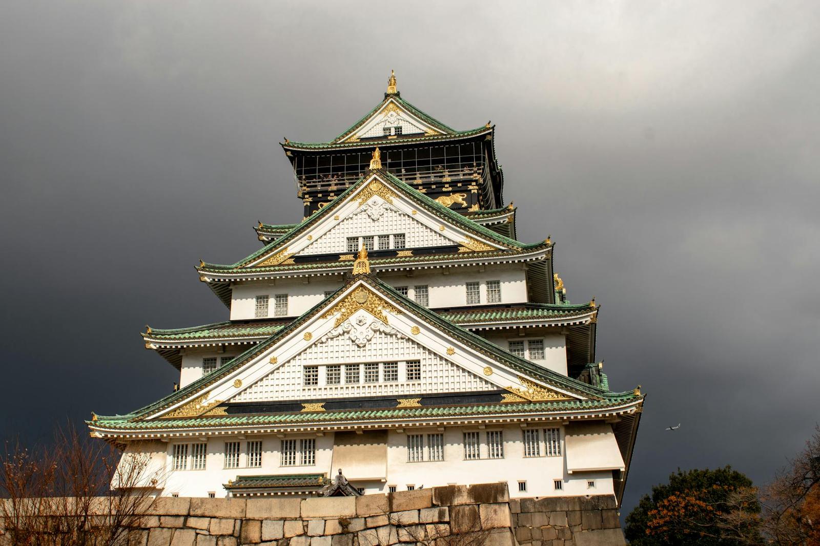 A tiered castle tower with gold trim against a darkening stormy sky