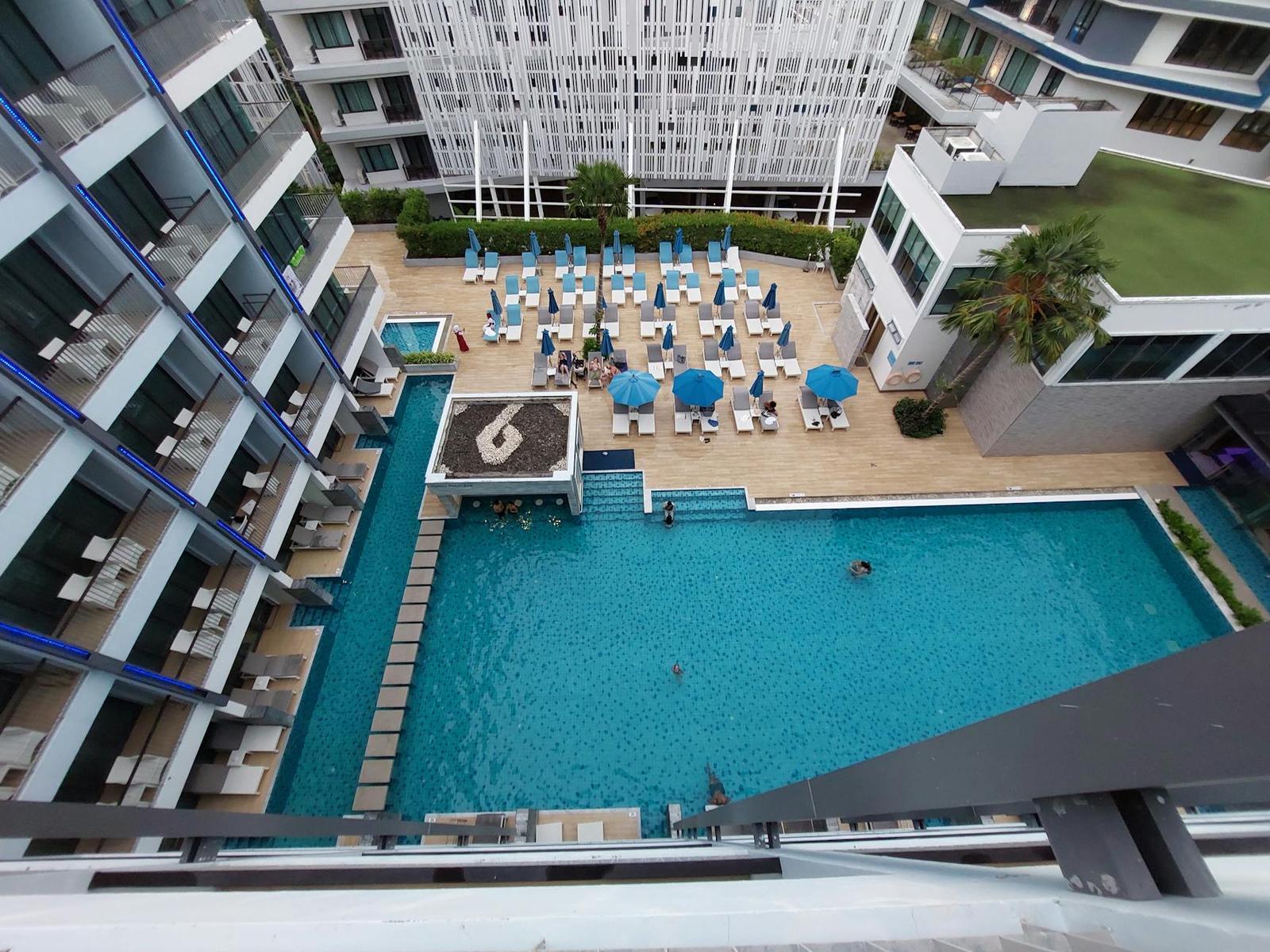 Aerial view of a resort pool deck with sun loungers between high-rise wings