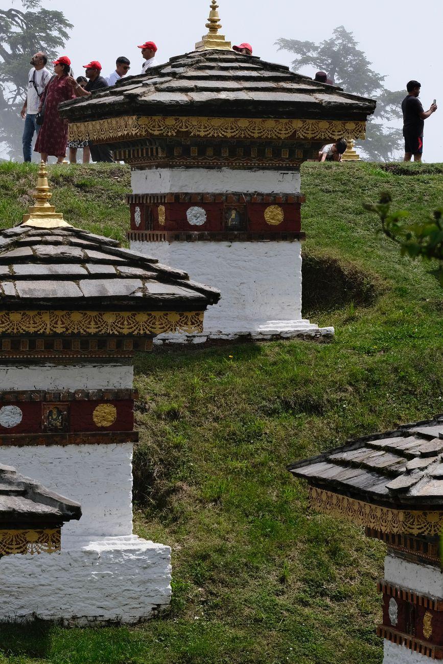 A scenic view of traditional Buddhist chortens on a grassy hill in Bhutan