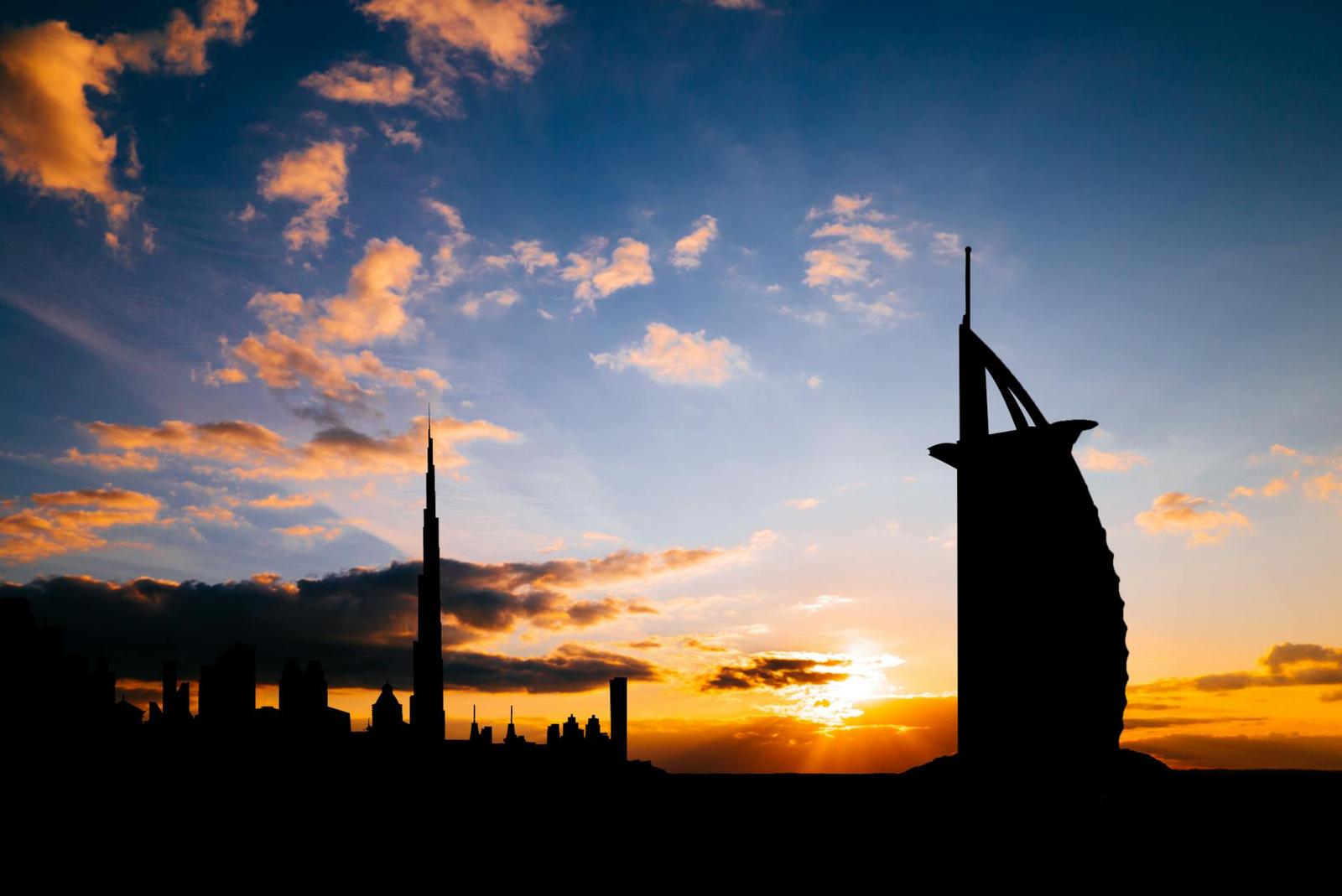 Silhouette of Dubai skyline featuring Burj Al Arab and Burj Khalifa at sunset