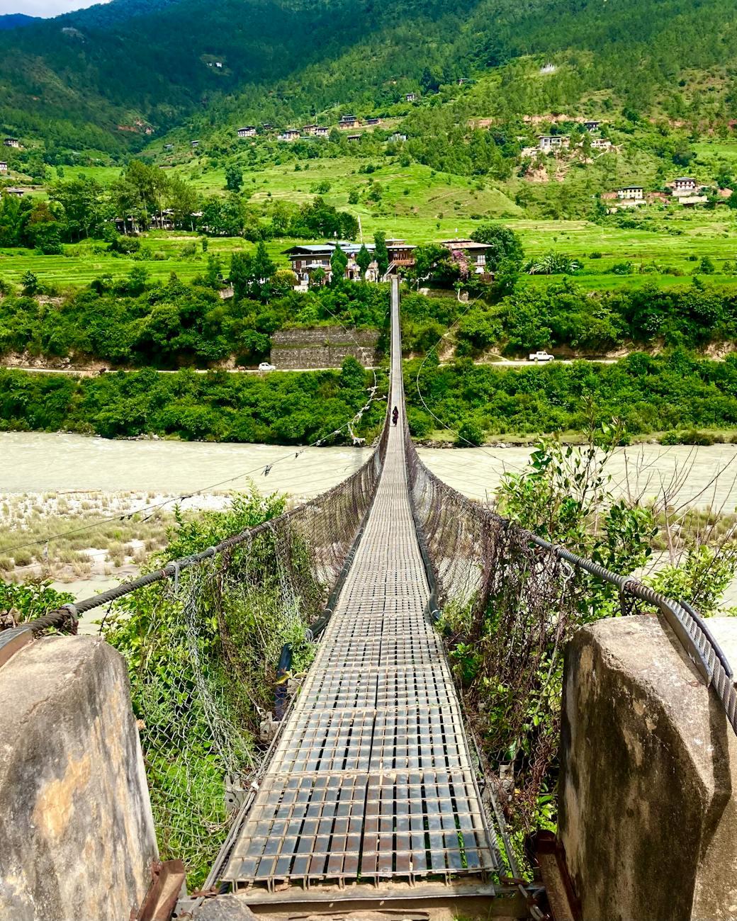 Explore Bhutan's stunning greenery from a rustic suspension bridge