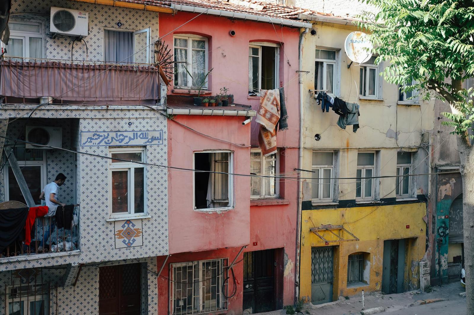 Row of weathered pink, yellow and white townhouses along a narrow street