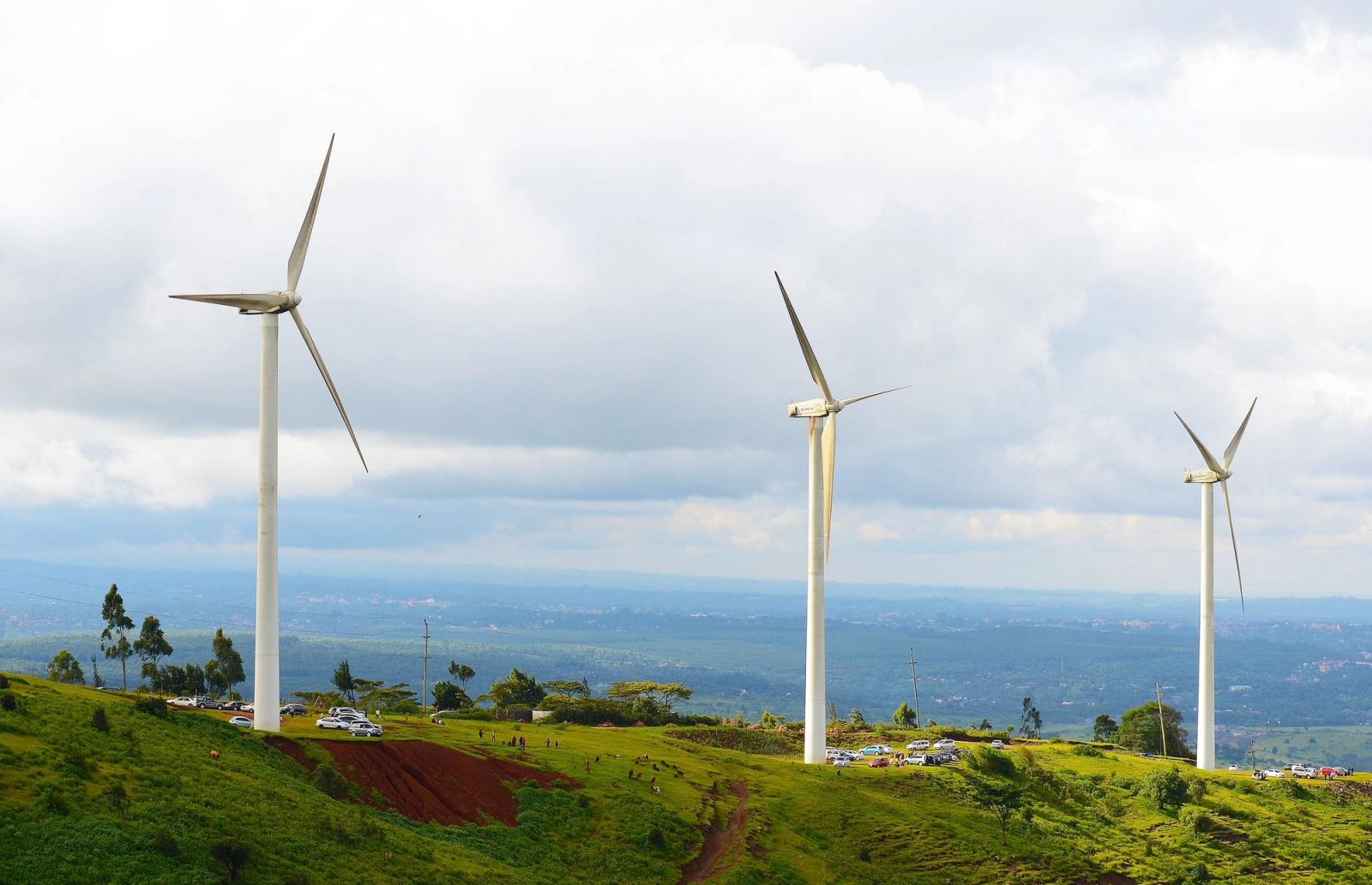Wind turbines on a green hill in Kajiado County, Kenya, under cloudy skies promoting clean energy
