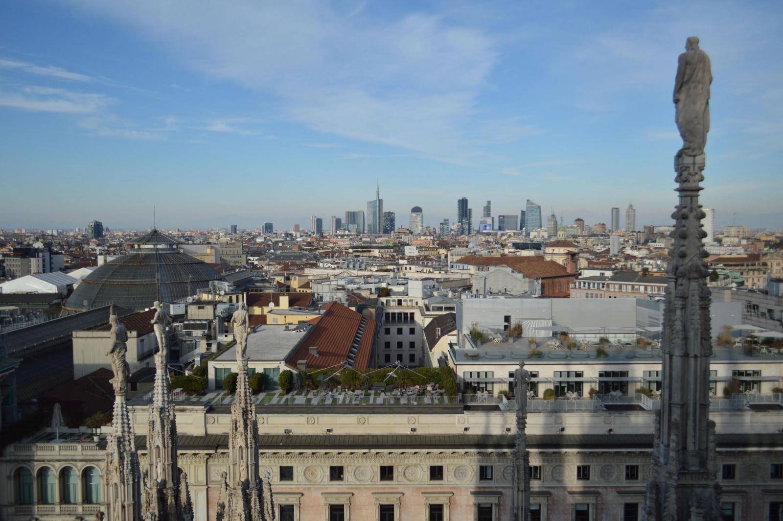 Captivating aerial view of Milan's skyline from atop the Duomo with a clear blue sky backdrop