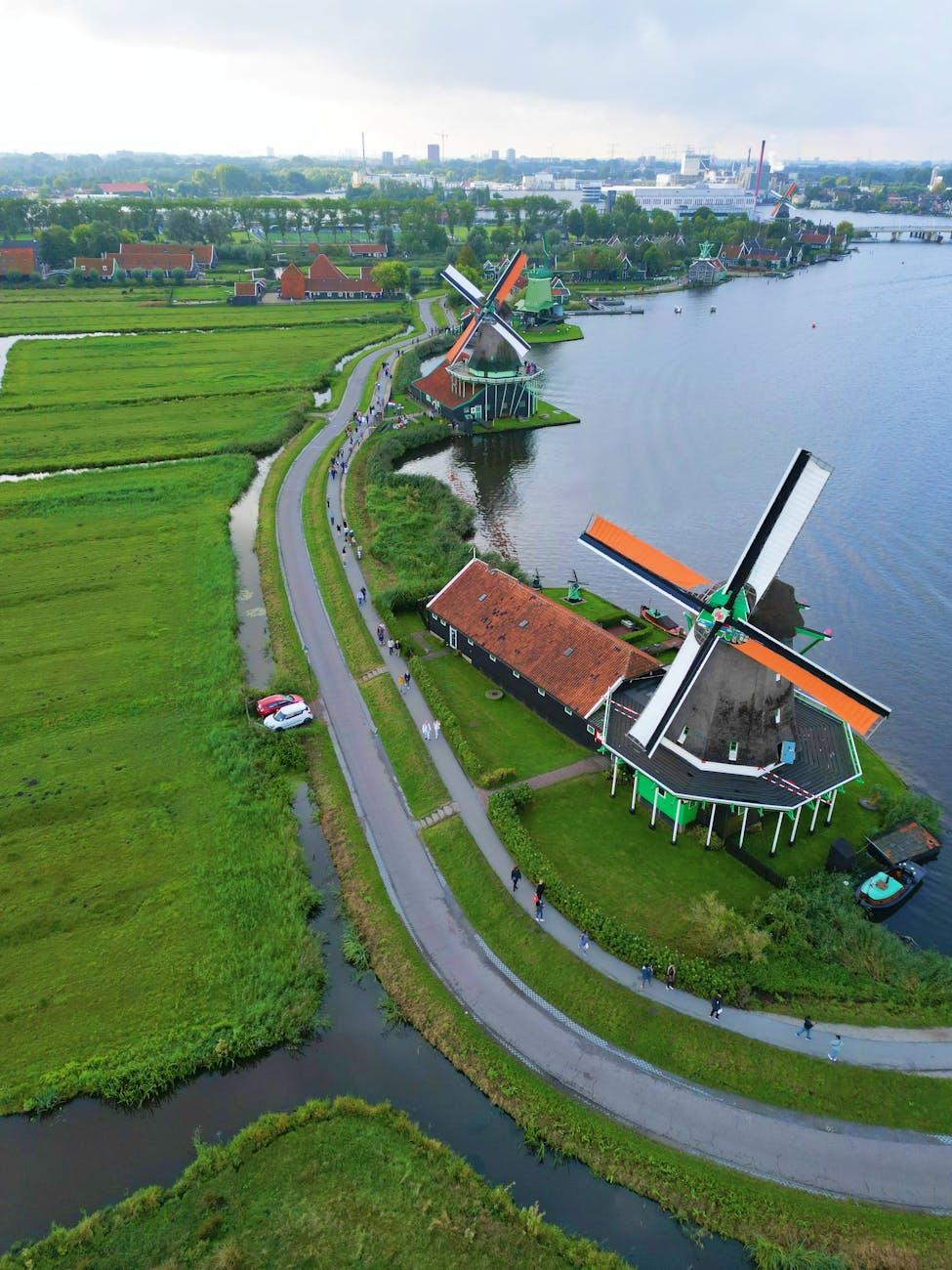 Aerial view of orange-bladed windmills along a canal road with cyclists