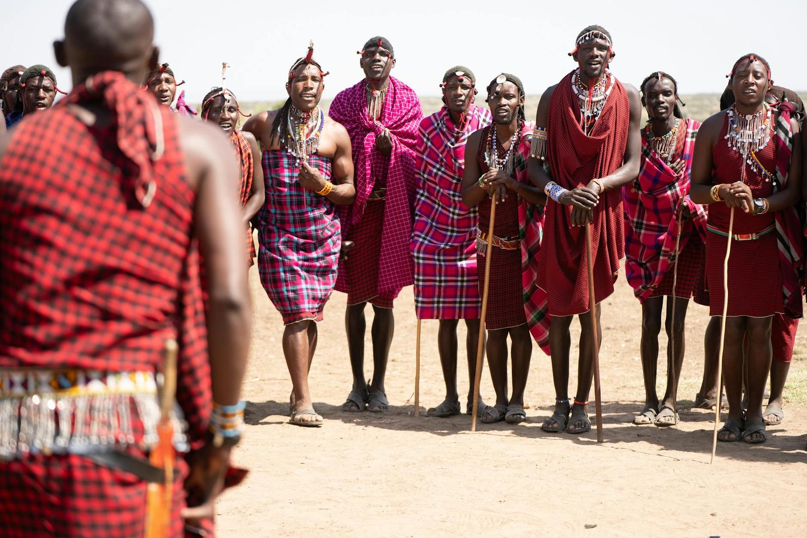 A group of Maasai people in red plaid gathered on open ground