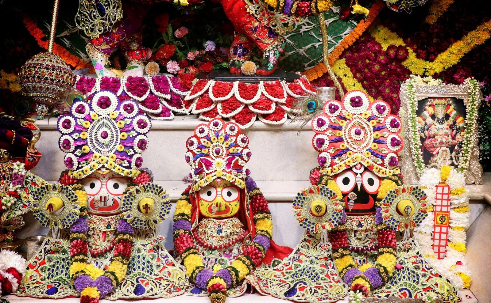 Three elaborately decorated deity idols adorned with flowers and beaded crowns