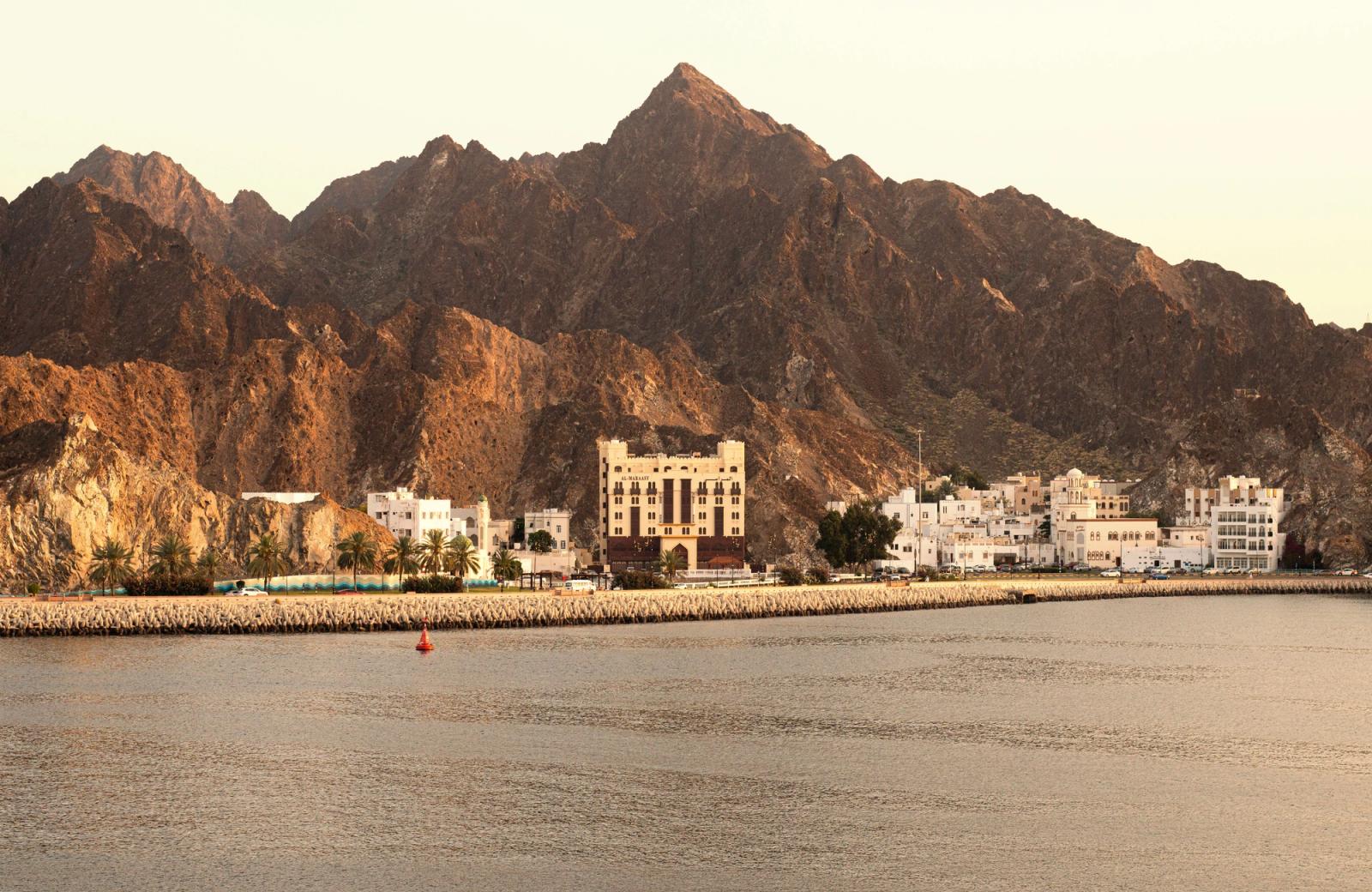 Picturesque view of Muscat's coastline with mountains and traditional architecture