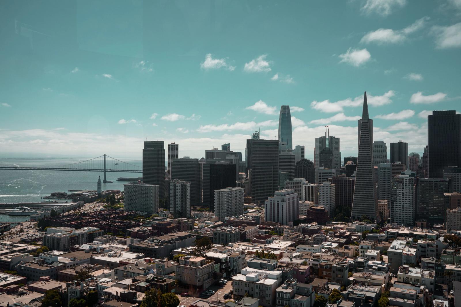 Stunning aerial view of San Francisco's skyline, featuring the iconic Bay Bridge under a bright sky