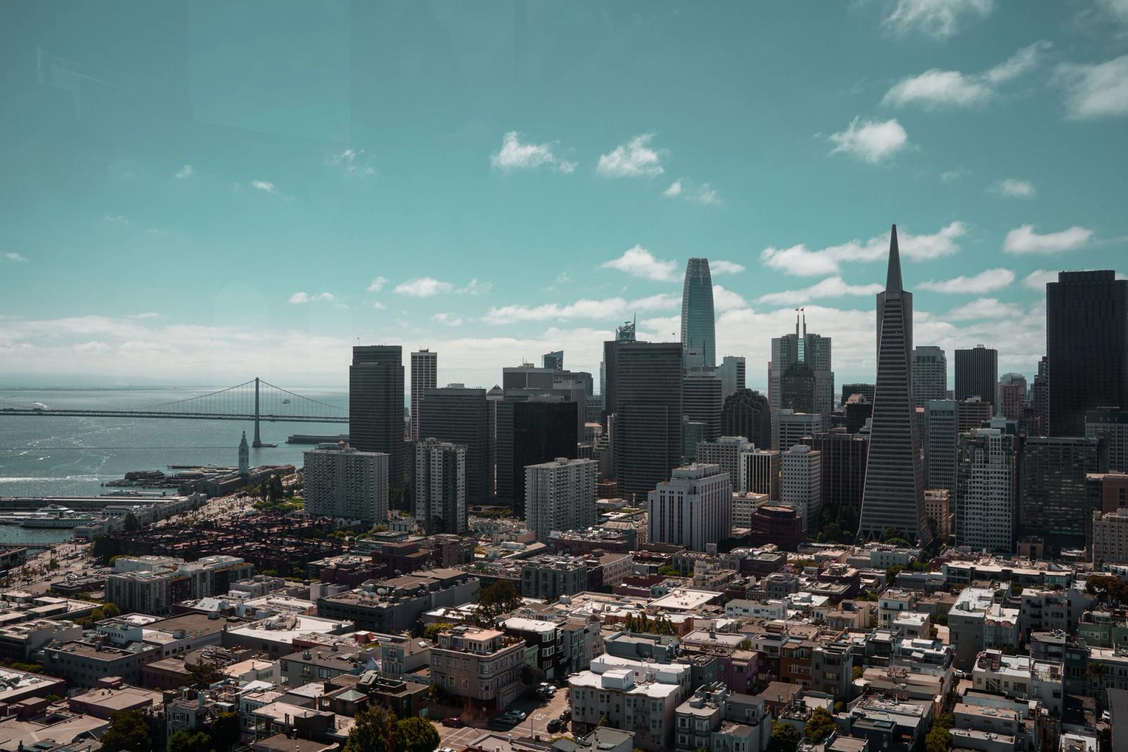 Stunning aerial view of San Francisco's skyline, featuring the iconic Bay Bridge under a bright sky