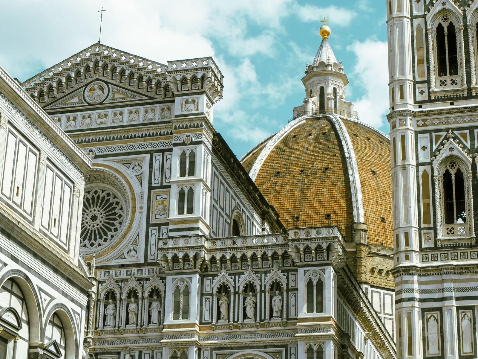 Close-up of a tiled cathedral dome and bell tower against a blue sky
