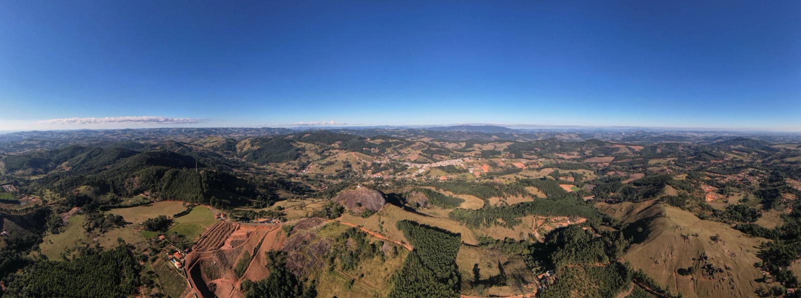 A breathtaking aerial view of Pedra Bela, SP, Brazil showcasing rolling hills and lush greenery under clear blue skies