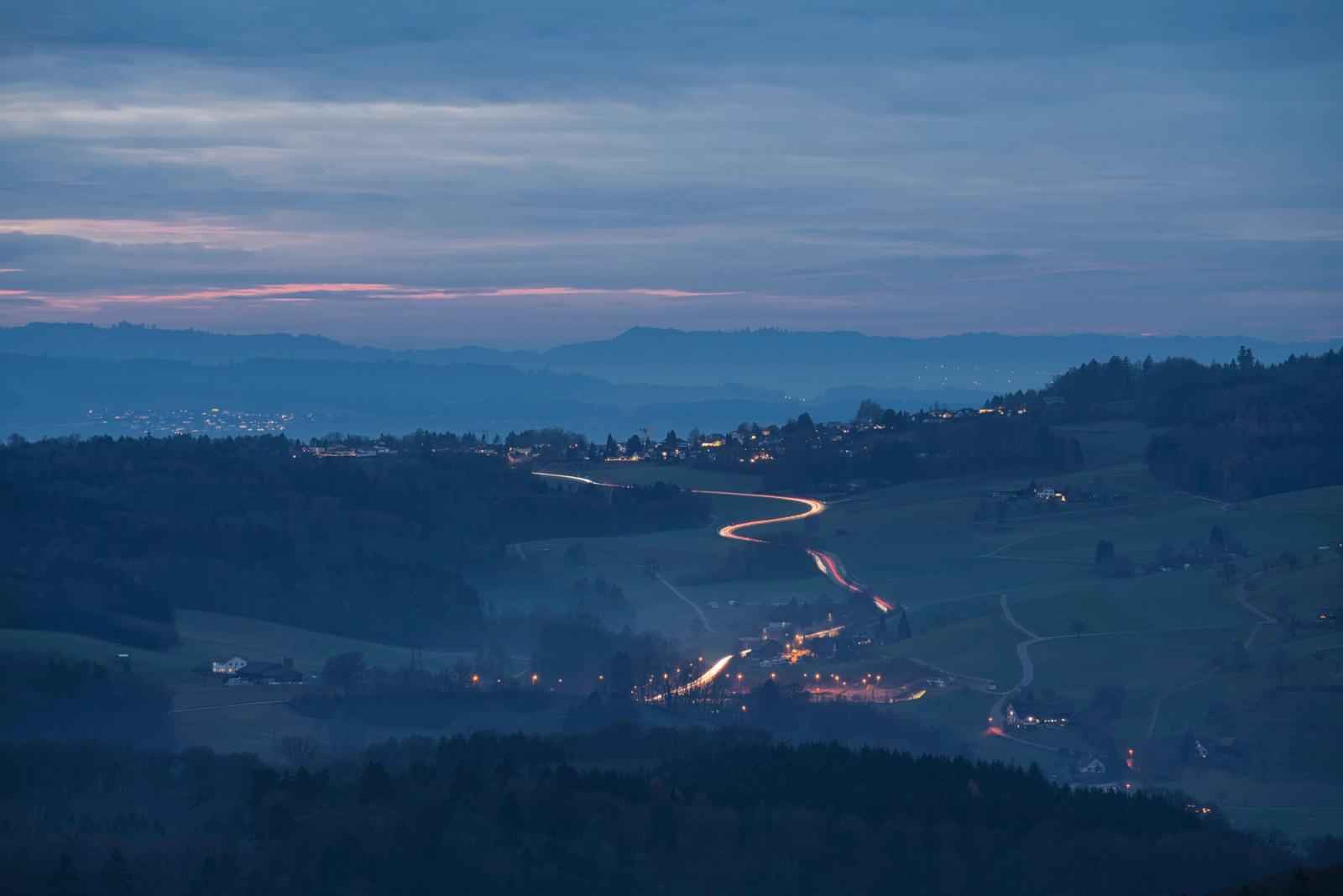 Blue hour aerial view of the Swiss countryside village with winding roads and twilight sky