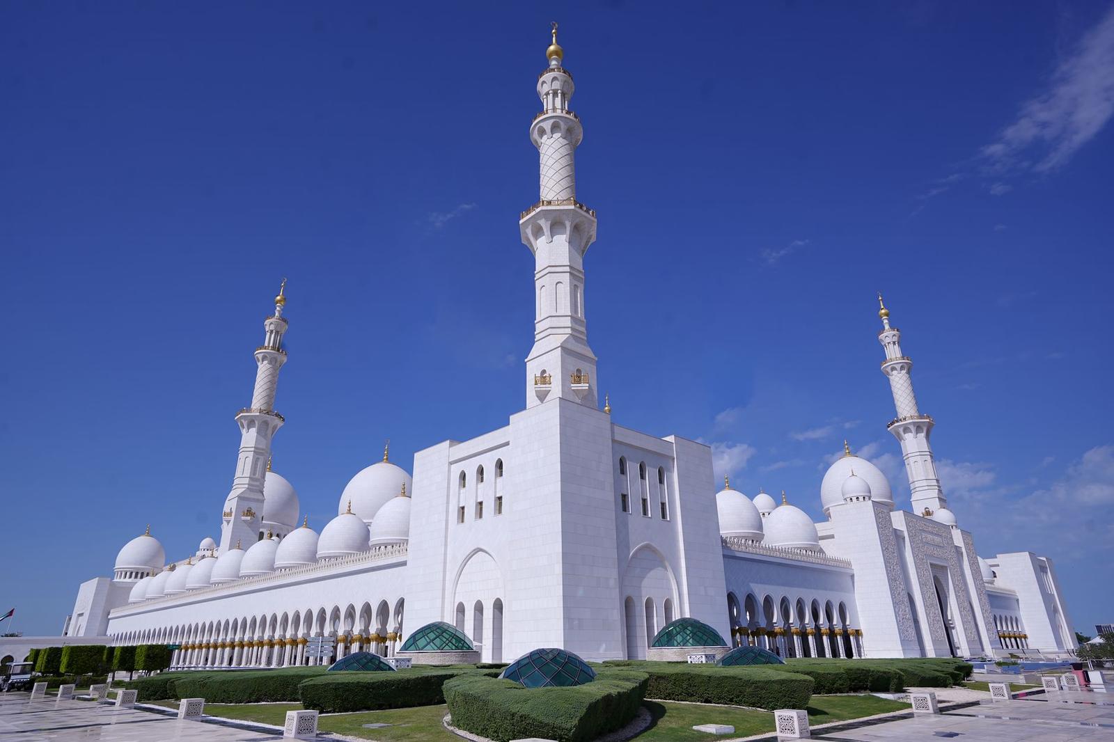 Grand white mosque with tall minarets under a clear sky