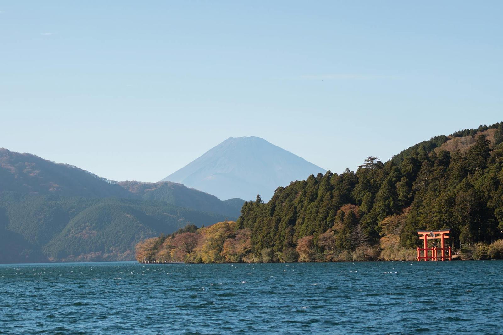 Picturesque view of Mount Fuji and red torii gate with lush greenery by Lake Ashi, Japan
